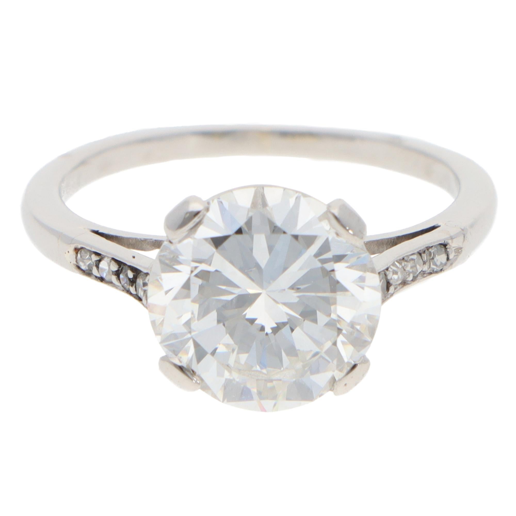An elegant vintage GIA-certified diamond ring set in platinum.

The piece predominately features a beautiful round brilliant-cut diamond. The diamond is four-claw set to centre within an open gallery setting, followed by 8 smaller diamonds on the