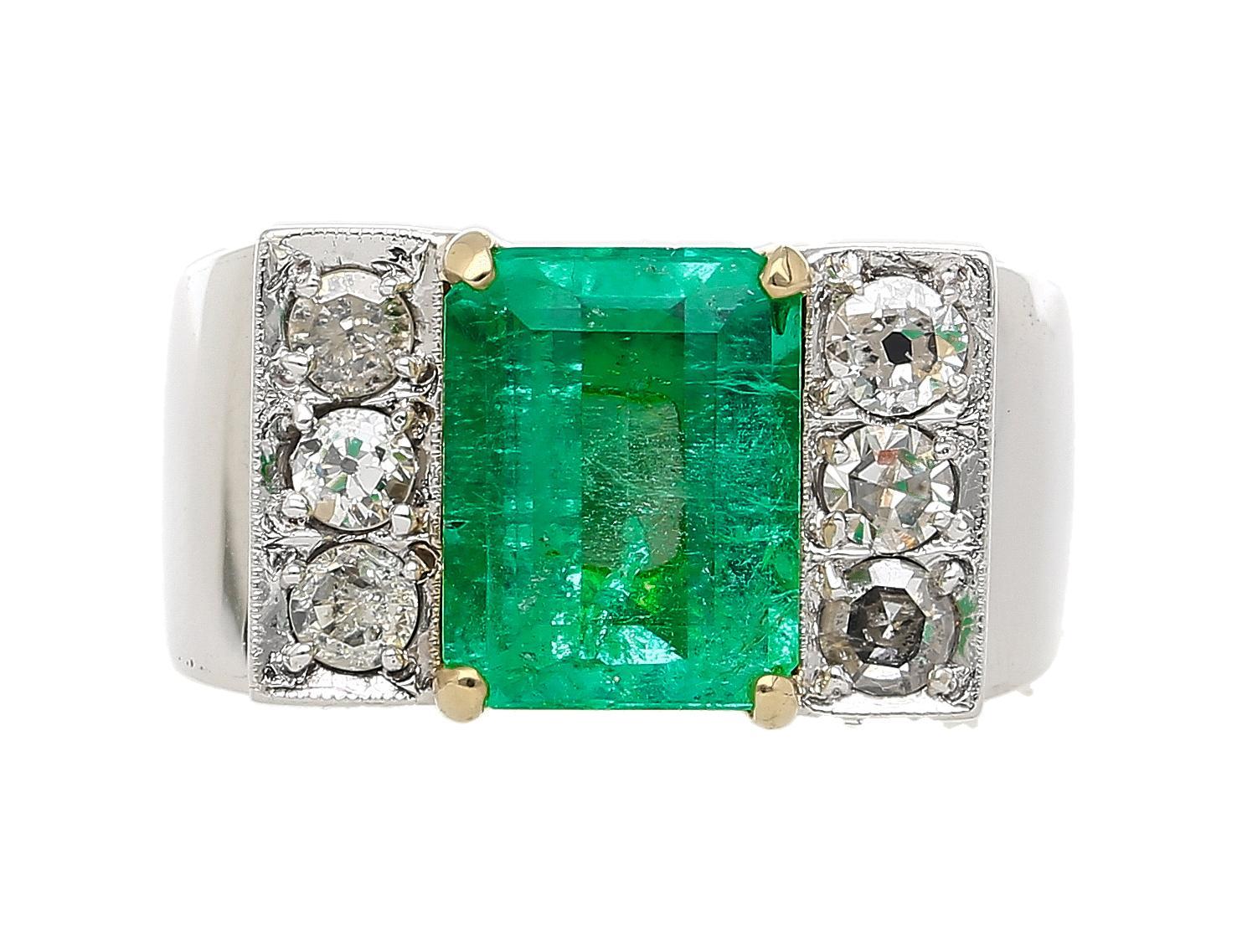 Bold vintage unisex ring sets a 3.04 carat vivid green emerald flanked by six antique old euro cut diamonds in 18k white gold. The ring’s wide shank gives it a substantial feel and a masculine edge. Ring Size 7, adjustable.

Details:
Item Type: