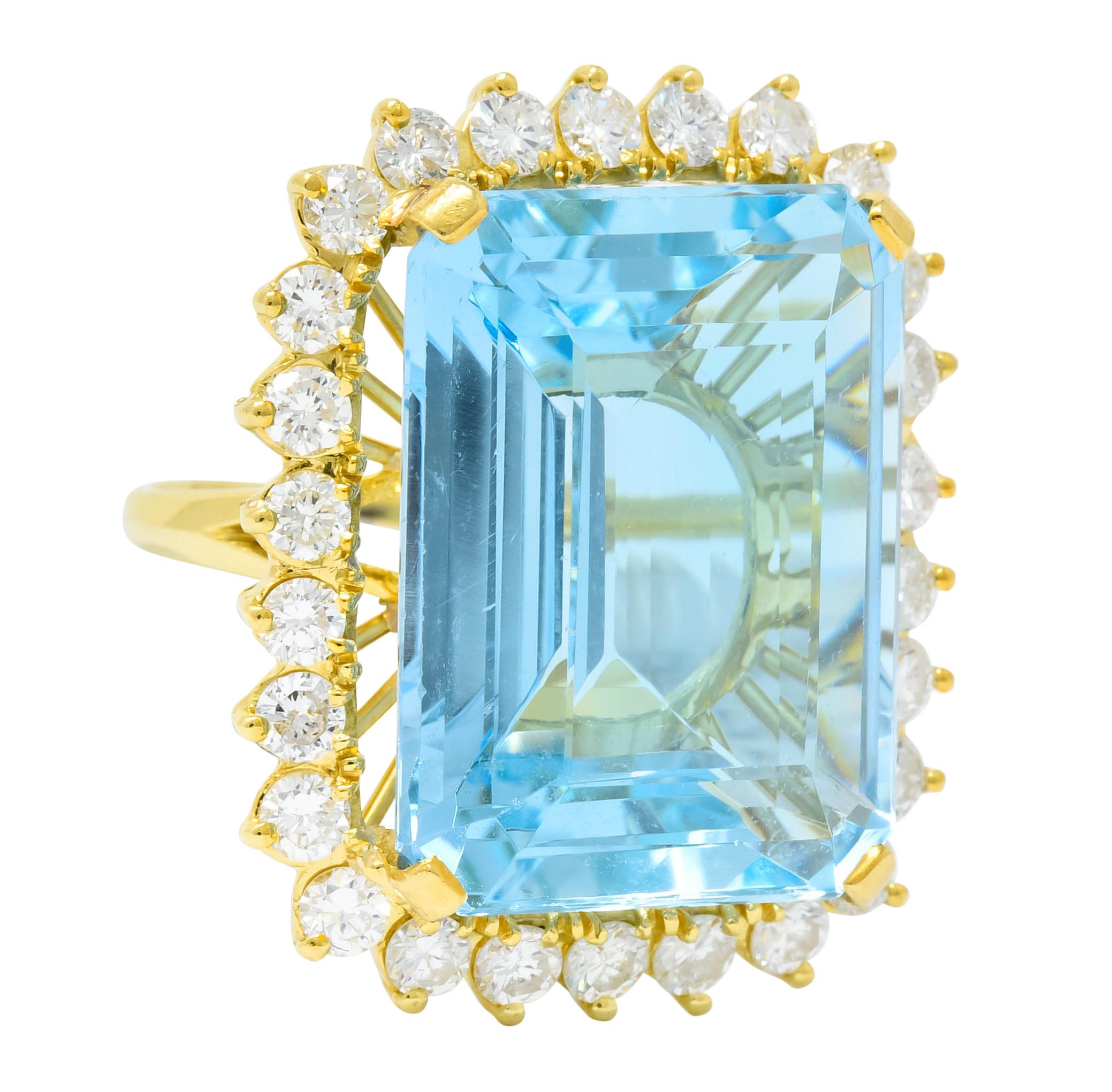 Cluster style ring centering a prong set rectangular step cut aquamarine weighing 28.00 carats; transparent and saturated sky blue color

Surrounded by twenty six prong set round brilliant cut diamonds weighing 2.50 carats, F to H in color and VS to