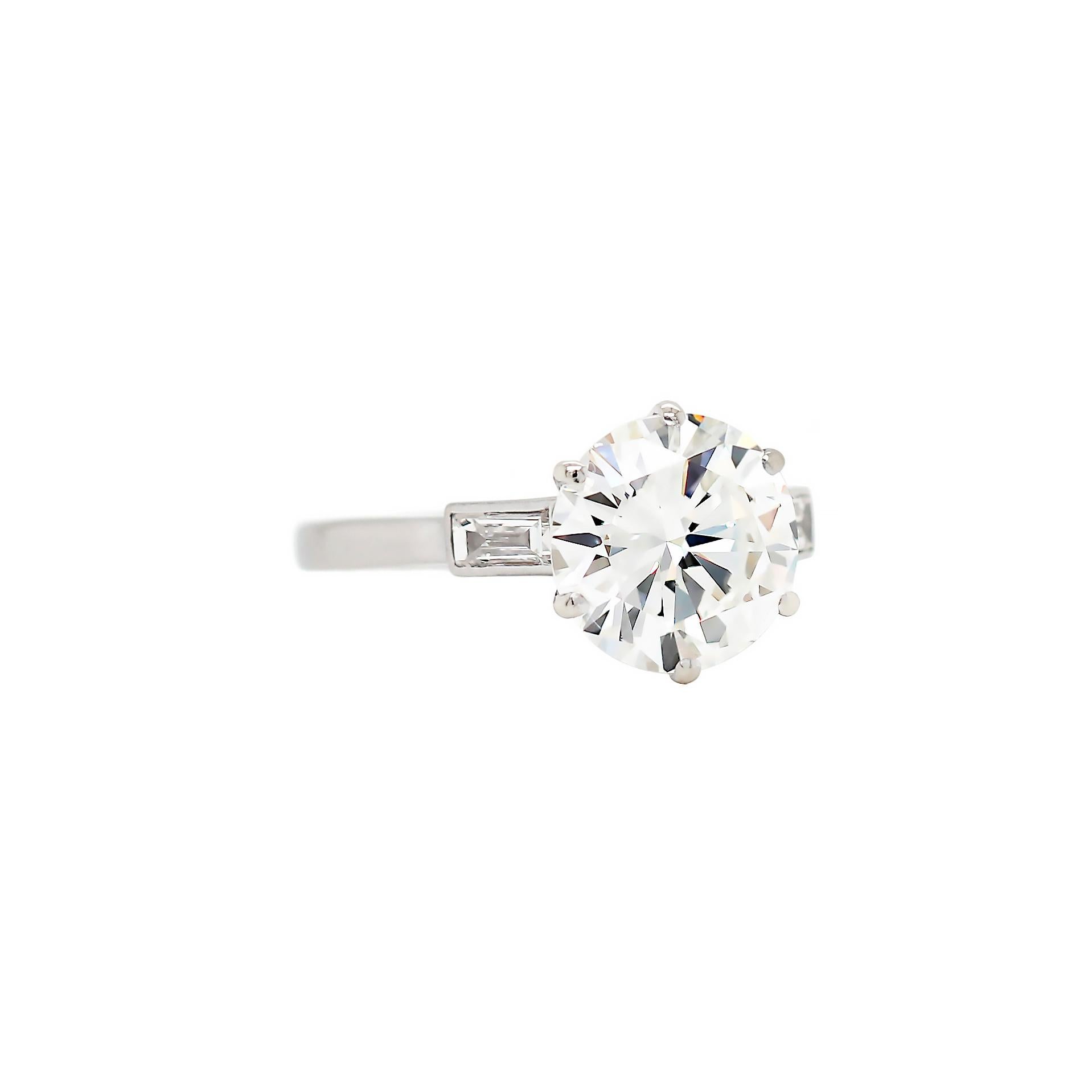 This exquisite Art Deco style engagement ring features an HRD certified round brilliant cut diamond weighing 3.14ct, graded H in colour and SI2 in clarity in a six claw open back setting. This beautiful stone is accompanied by a horizontally set