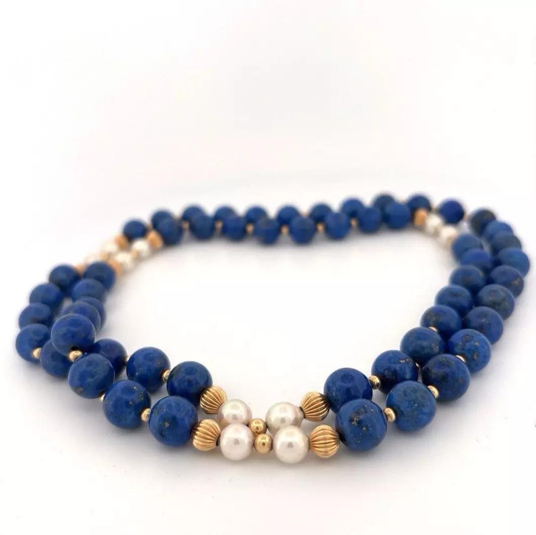 This vintage 32-inch endless necklace features natural lapis lazuli beads, measuring an average of 10.25mm each, accented by ten (10) cultured Akoya pearls averaging 7.33mm. The pearls and lapis are separated by 6.14mm 14K yellow gold corrugated