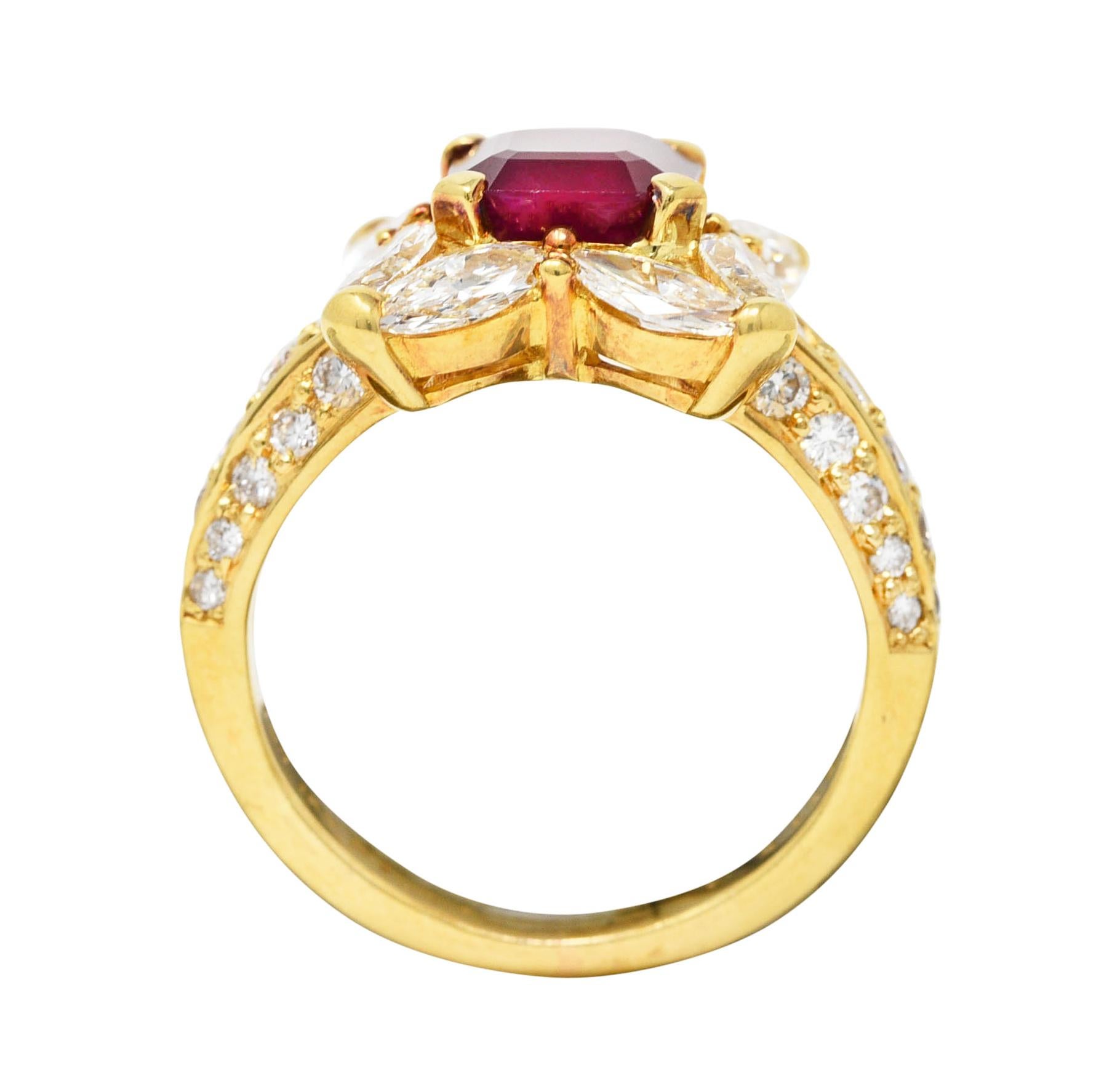 Centering an emerald cut ruby weighing 1.93 carats total - transparent medium red in color. Natural Vietnamese in origin - prong set with marquise cut diamond halo surround. Arranged as cushion shape and flanked by pavé set round brilliant cut