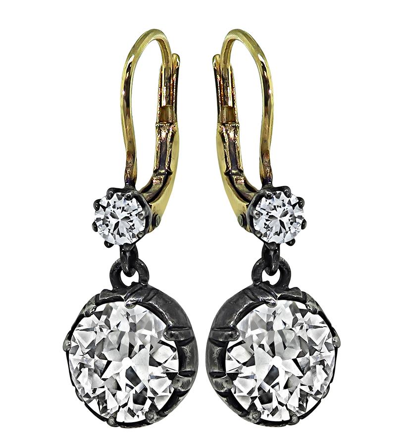 This is an elegant pair of silver and gold earrings. The earrings feature sparkling 2 large old mine cut diamonds that weigh approximately 3.52ct. The color of these diamonds is J-K with VS1 clarity. The two large diamonds are accentuated by two