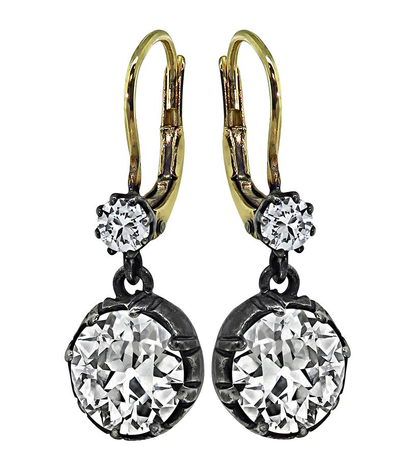 Se trata de un elegante par de pendientes de plata y oro. Los pendientes presentan 2 brillantes diamantes talla antigua que pesan aproximadamente 3,52 ct. El color de estos diamantes es J-K con claridad VS1. Los dos diamantes grandes están