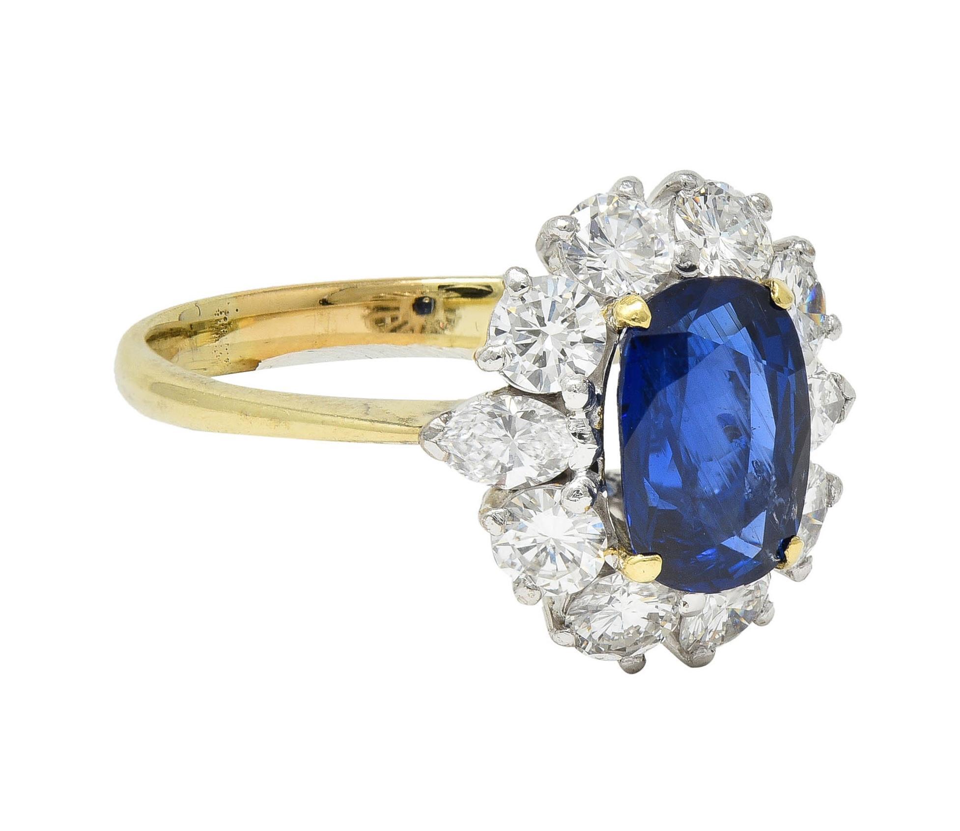 Centering a cushion cut sapphire weighing approximately 2.06 carats total - transparent deep blue 
Natural Burmese in origin with no indications of heat treatment 
Prong set in gold with a platinum halo surround of diamonds
Round brilliant and