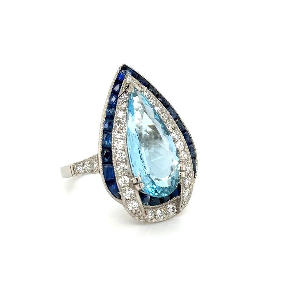 Simply Beautiful! Stylish and Finely detailed Vintage Aquamarine, Diamond and Sapphire Platinum Cocktail Ring. Centering a securely nestled Hand set Beautiful 3.80 Carat Pear Aquamarine Gemstone, surrounded by OEC Diamonds, weighing approx. 0.64tcw