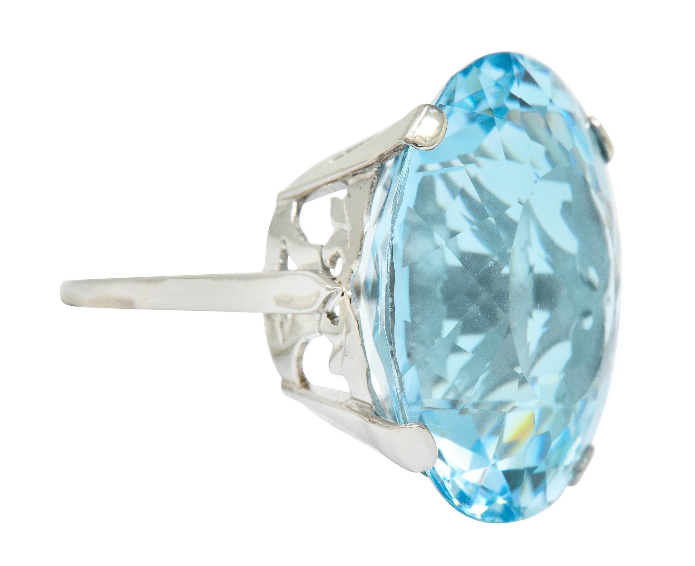 Centering a substantial oval mixed cut aquamarine weighing 39.48 carats, eye-clean and a bright light blue color

Prong set in mounting with an intricately pierced gallery featuring a stylized bow motif

Tested as 18 karat gold and stamped with