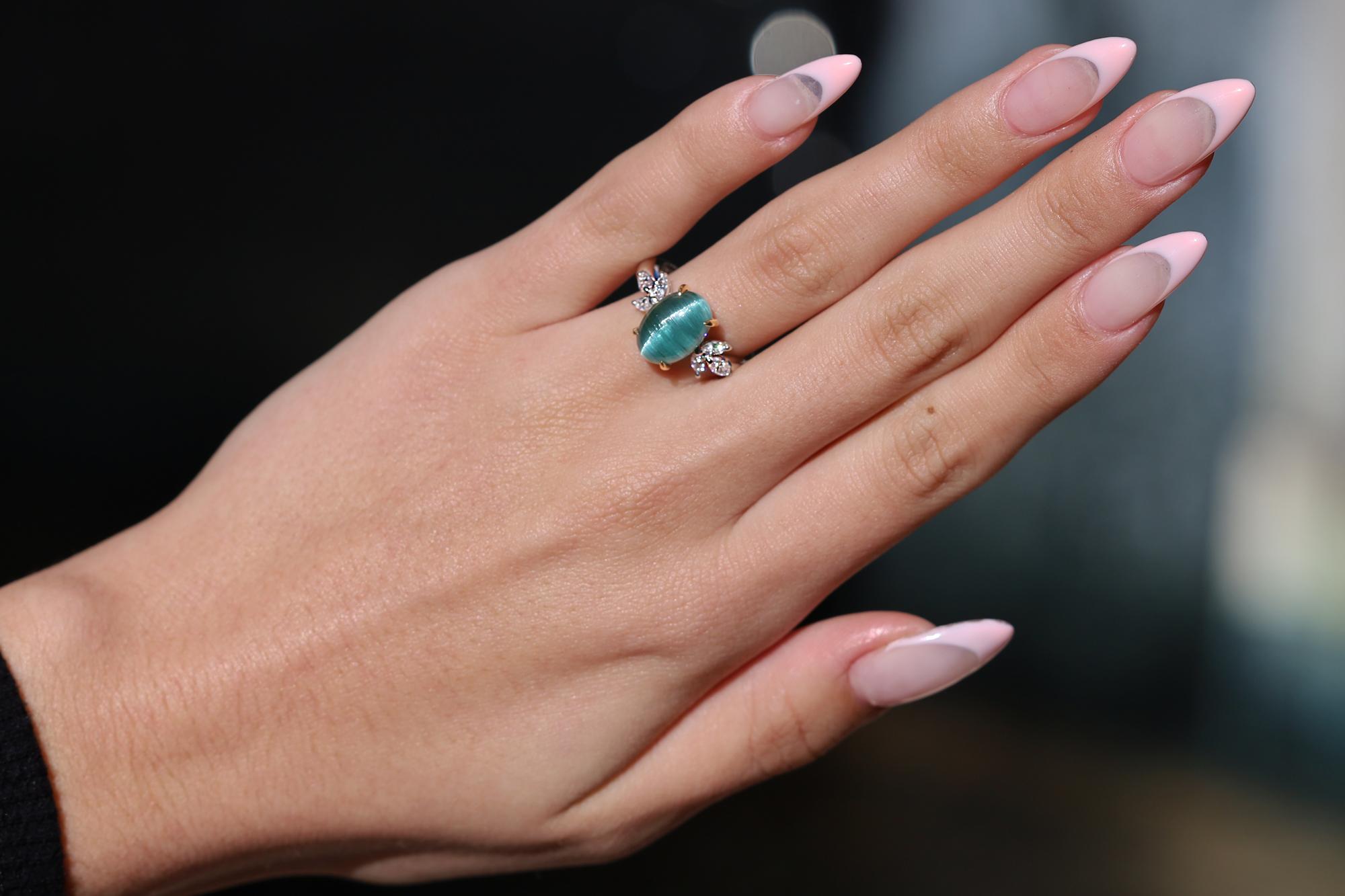 Centered by a scintillating, sparkling indicolite tourmaline, this Cat's Eye cocktail ring is a vintage stunner. The cabochon weighing 4 carats exhibiting a distinct 