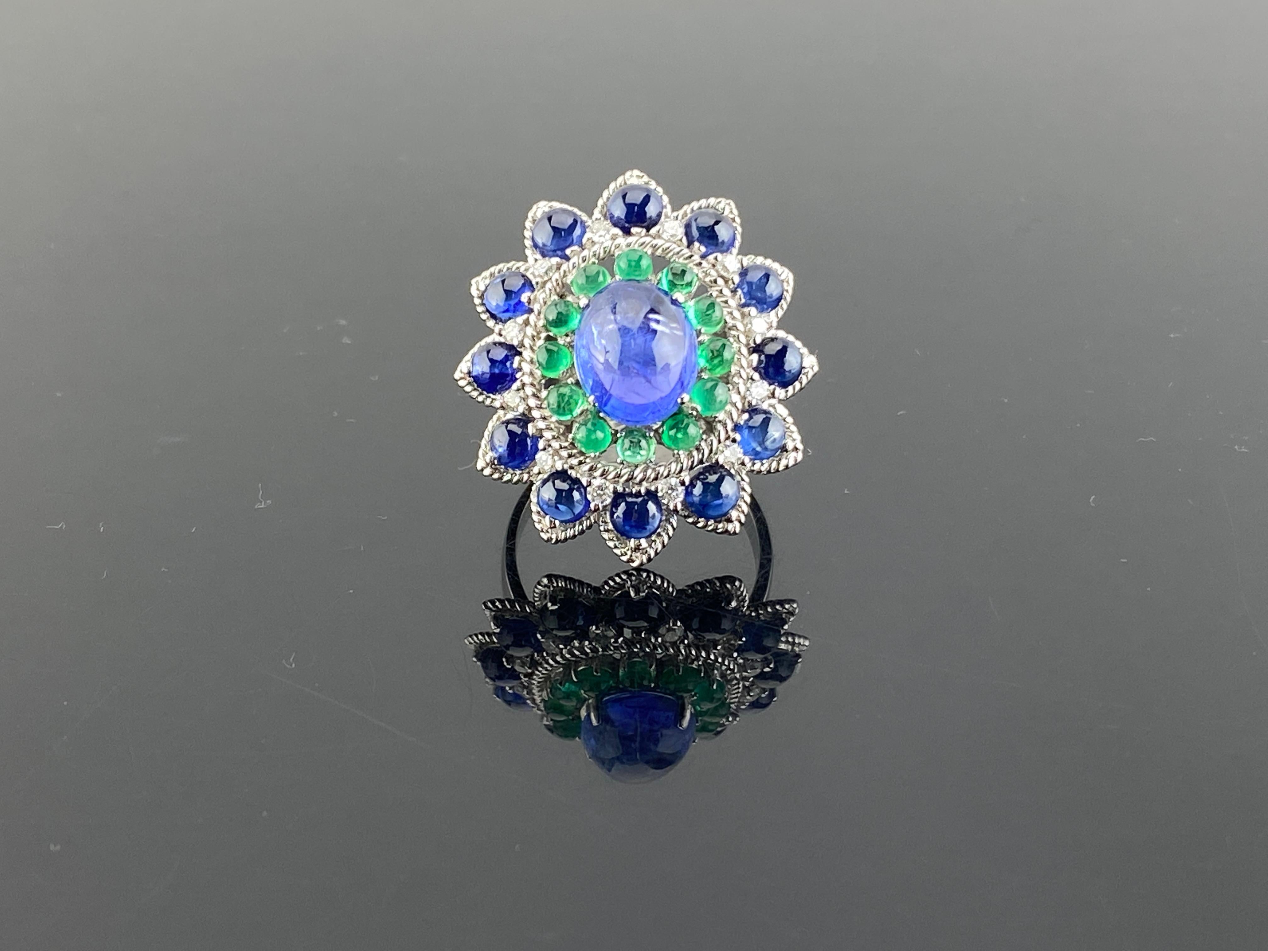 This intricately hand crafted ring made with the center stone being a bluish hue tanzanite , it is surrounded by emeralds of Colombian origin , diamonds and then round blue vivid blue sapphires . The ring plays on the shades and contrast of the