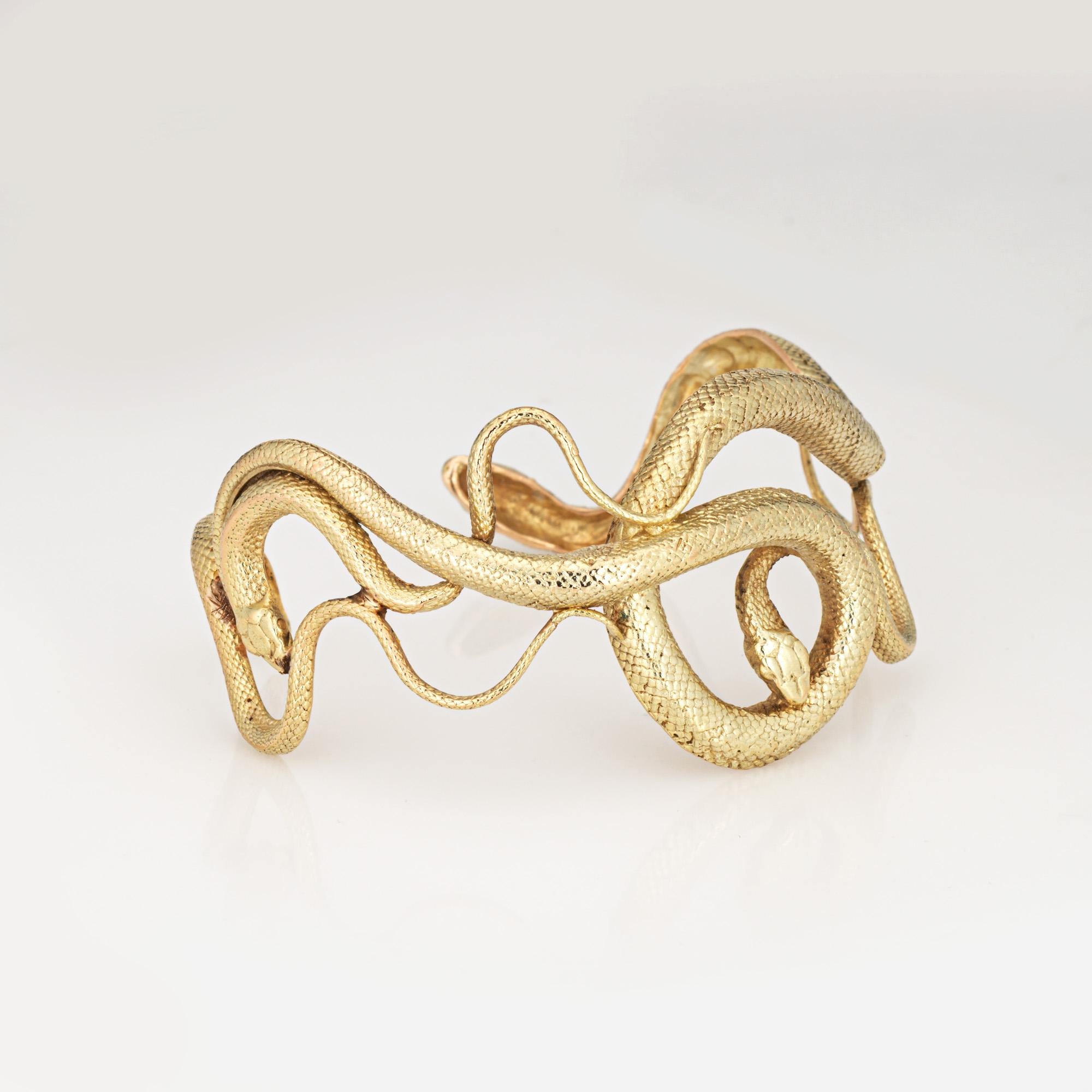 Finely detailed vintage snake cuff bracelet crafted in 18 karat yellow gold (circa 1970s to 1980s). 

Long a symbol of power and mystery, the striking and unique bracelet highlights four snakes that coil and wrap around the cuff. The four-snake