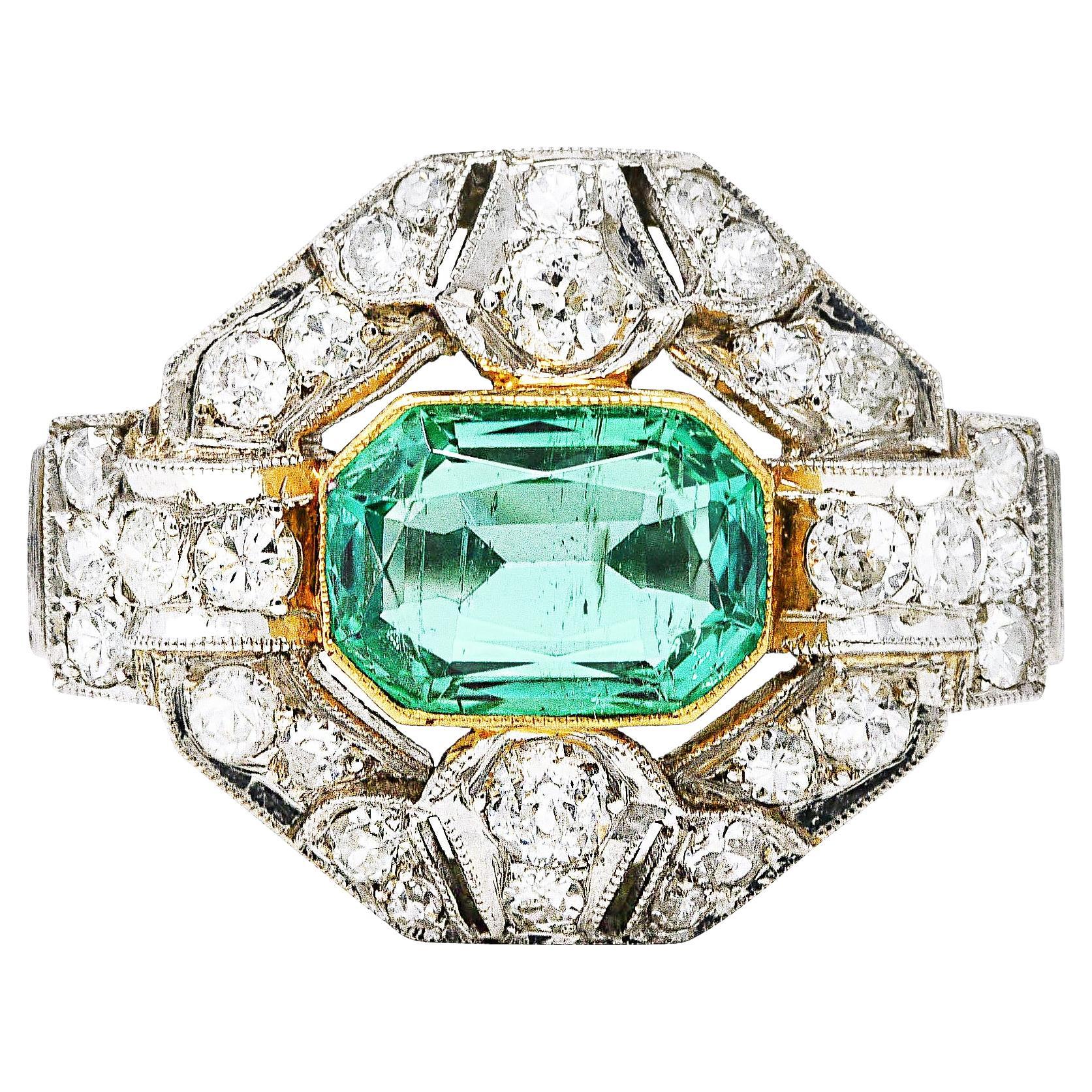 East to West cluster ring is designed as a hexagonal form with arched banding and stepped shoulders. Centering an emerald cut Colombian emerald weighing approximately 2.05 carat. Transparent green in color with no indications of treatment. Bezel set
