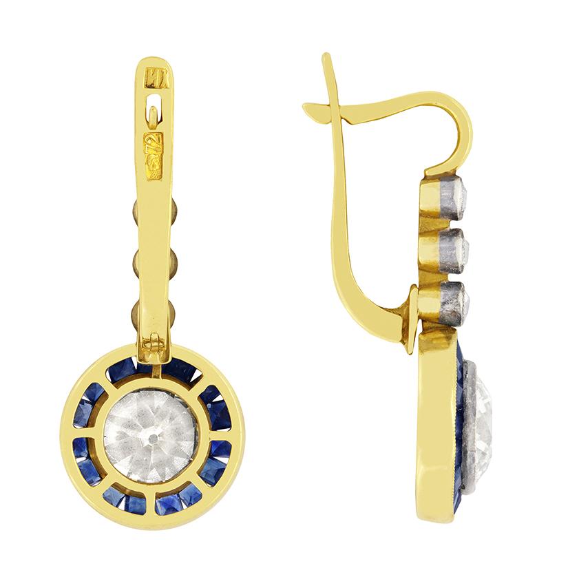 A superb pair of drop earrings featuring old cut diamonds and blue sapphires. The stunning pair of matching diamonds at the bottom of the earrings are 2.10 carat each and have been certified by EDR as I-J in colour and VS in clarity. Surrounding