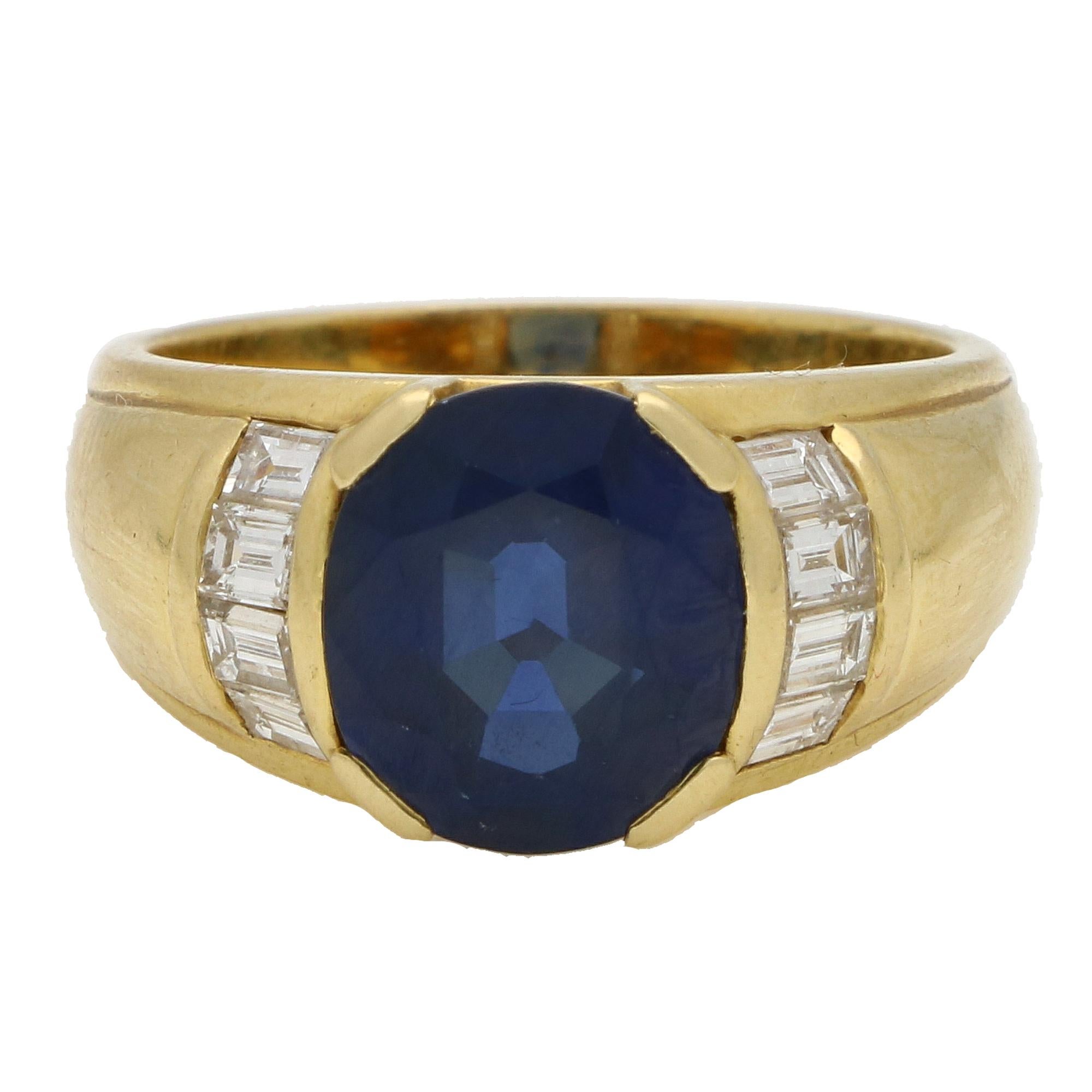 A beautiful large vintage blue sapphire and diamond ring set in 18k yellow gold. 

The ring is predominately set with a large oval blue sapphire, which is securely four claw set with centre. To either side of the sapphire are four sparkly baguette