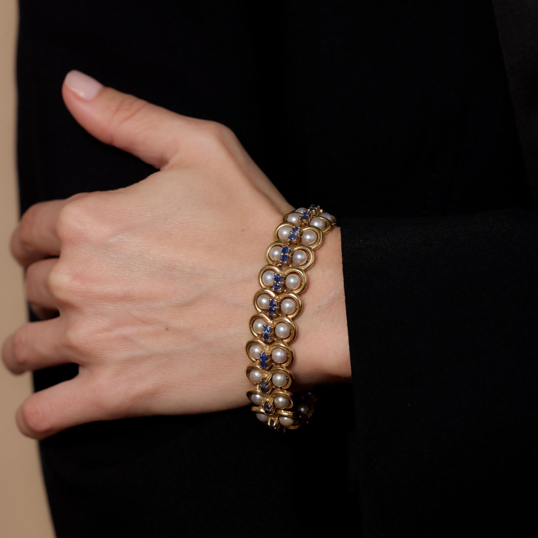 This vintage 14k yellow gold bracelet showcases 44 pearls measuring approximately 5.12mm, accented by 44 round brilliant cut blue sapphires totaling 4.50 carats. Crafted in the 1980s, it is hallmarked with a purity mark, measures 7.5 inches in