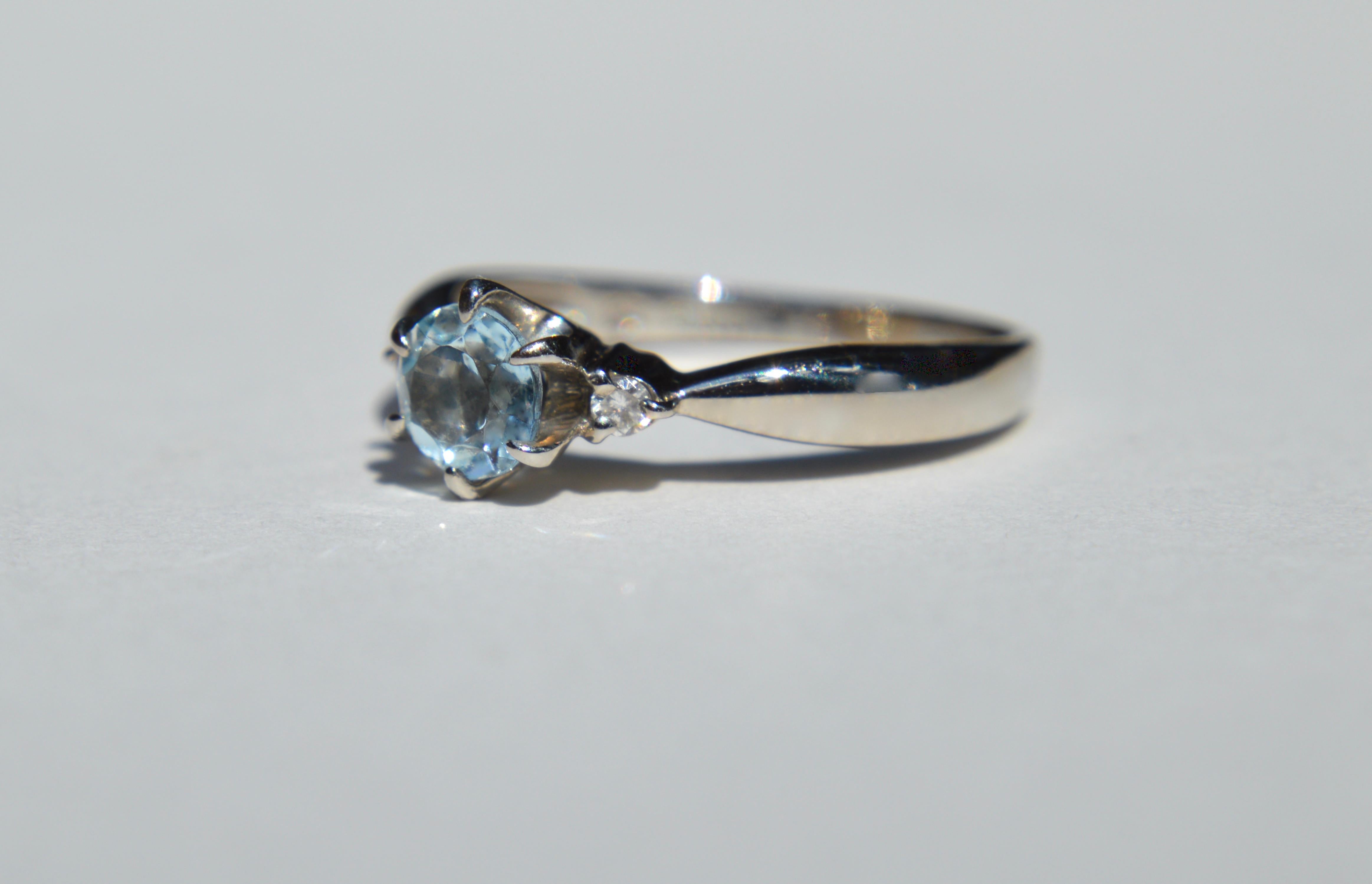 Vintage c1980s .46 carat round cut natural aquamarine with two .03 carat round cut diamonds set in solid platinum. In excellent condition. Size 6, can easily be resized by your local jeweler. Marked as Pt900 for platinum. The beautiful aquamarine