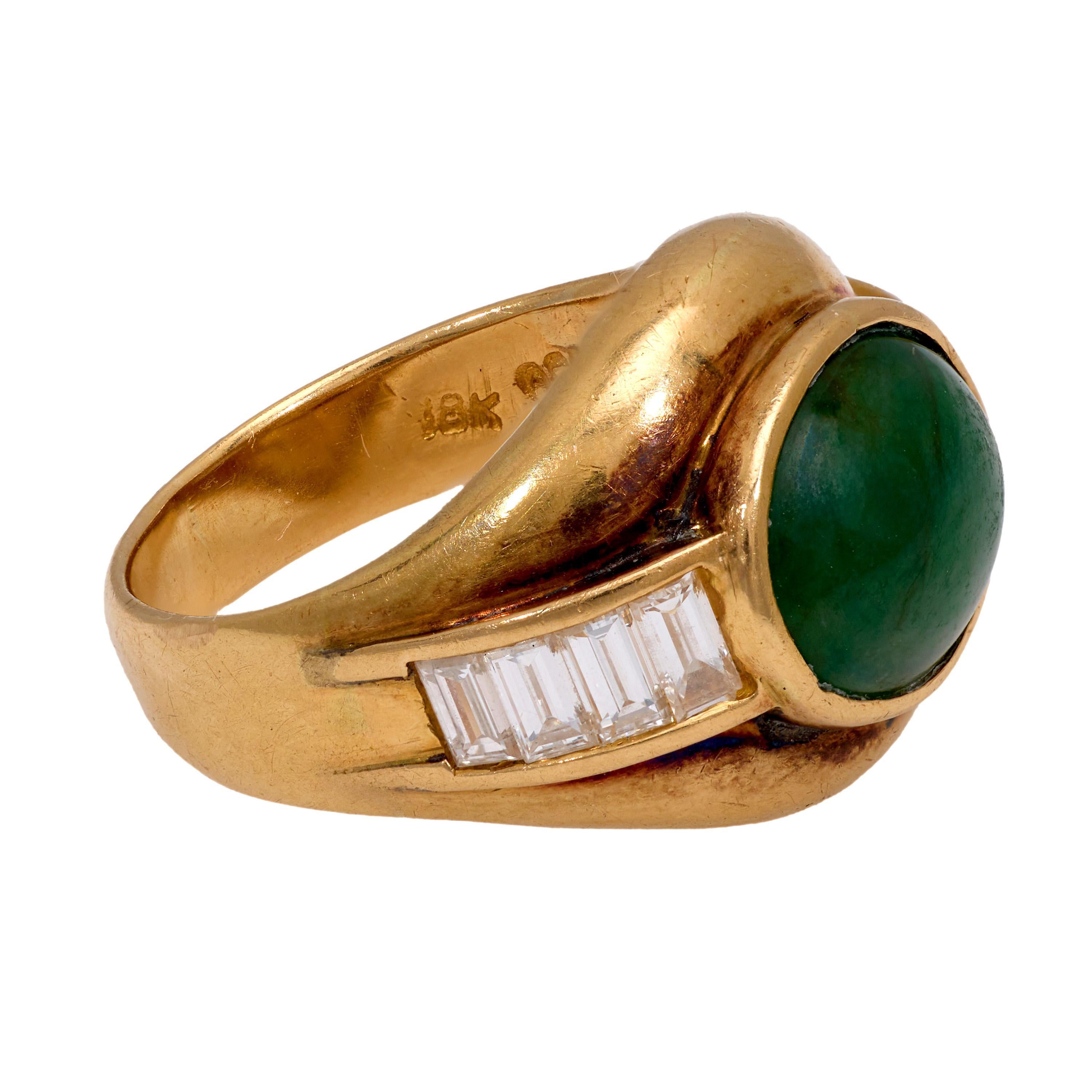 This vintage ring from the 1970s features a cabochon cut jade weighing approximately 4.65 carats, set in warm 18k yellow gold. Flanking the center stone are eight baguette cut diamonds totaling approximately 0.80 carats, graded G-H color and VS