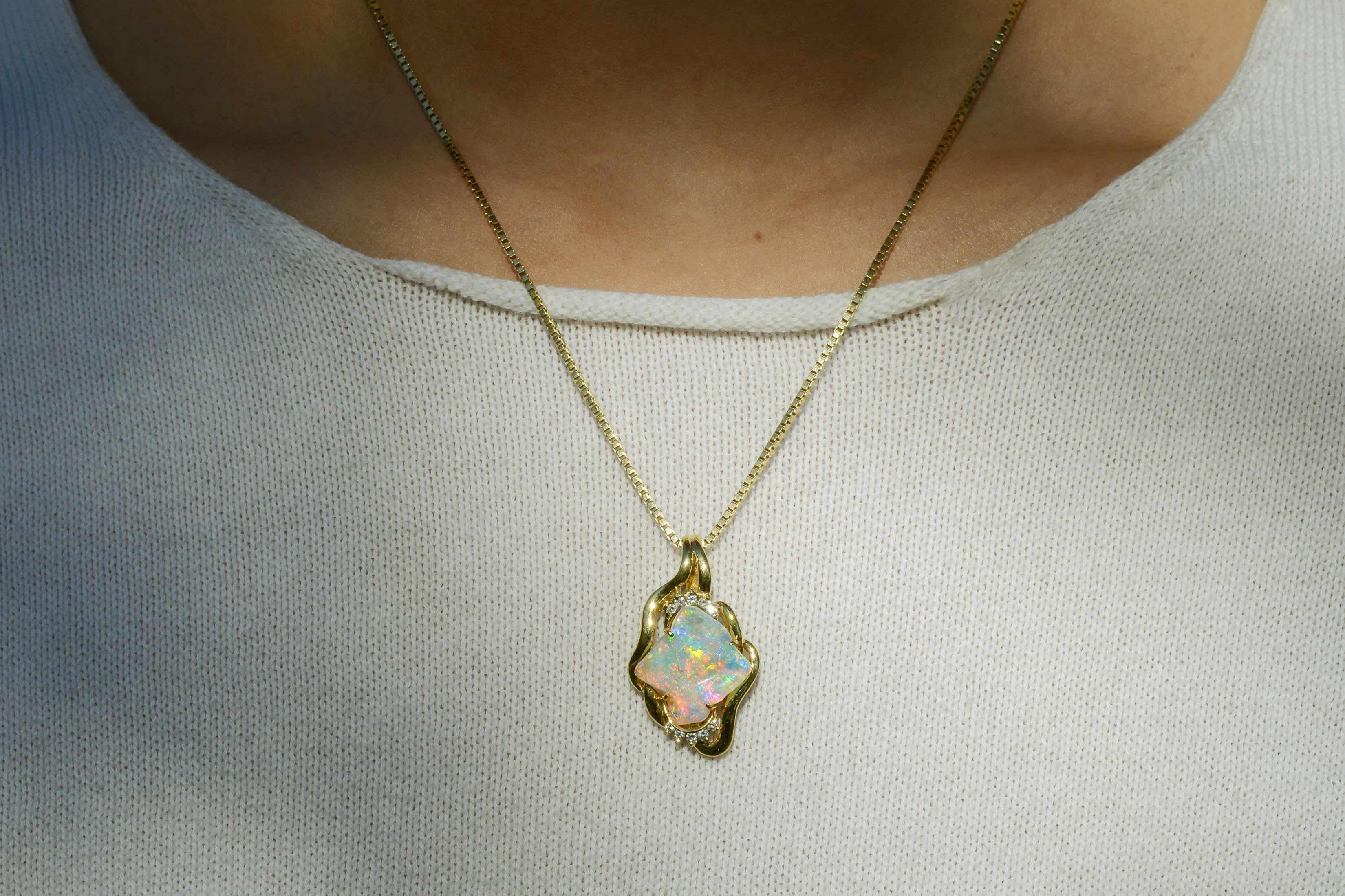 A truly beautiful Australian opal centers on this pendant. The opal displays rich, flashing blues and greens, flowing into fiery red and orange. We love the irregularly shaped opal that is accentuated by the buttery 18k yellow gold frame studded
