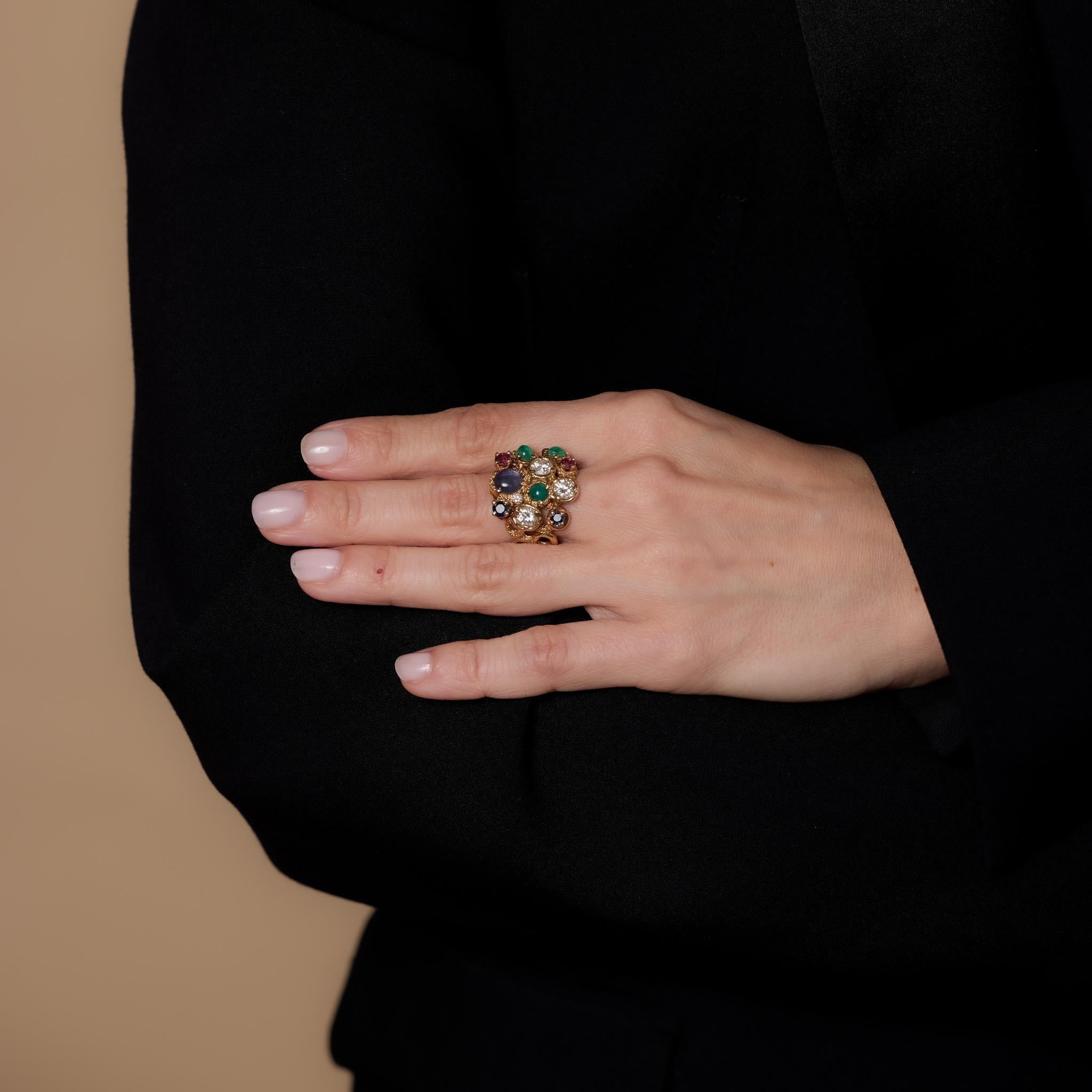 Cette bague cocktail vintage en or jaune 14k met en valeur 4 diamants ronds et ronds de taille brillant (1,20 carats, couleur H, pureté VS-SI), 3 émeraudes de taille cabochon (1,30 carats), 2 saphirs ronds de taille brillant et 1 saphir de taille