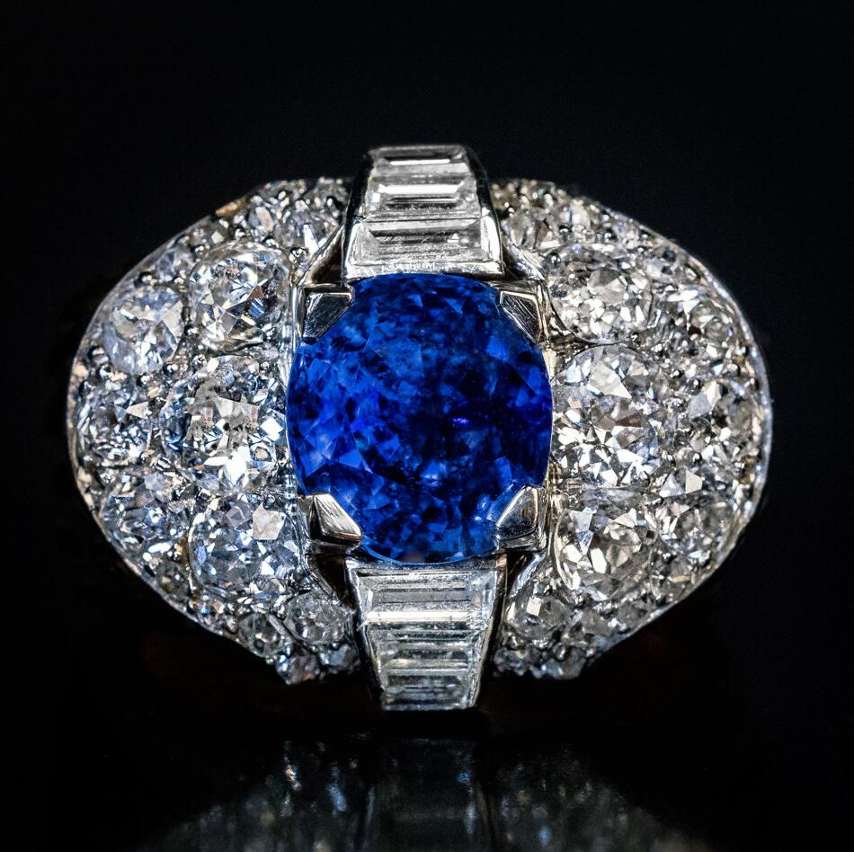 Circa 1950

This chunky vintage ring is crafted in platinum and 18K gold. The ring features a natural unheated 5.06 ct Ceylon sapphire of a rich cornflower blue color. The sapphire is framed by baguette, old European, old cushion, and old single cut