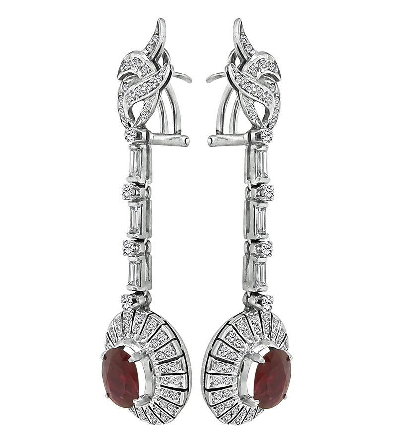 This is a gorgeous pair of 14k white gold drop earrings. The earrings feature lovely oval cut rubies that weigh approximately 5.00ct. The rubies are accentuated by sparkling baguette and round cut diamonds that weigh approximately 2.50ct. The color