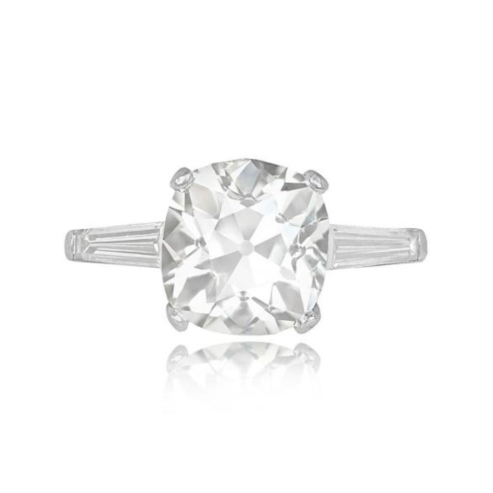 This vintage engagement ring showcases a magnificent 5.19-carat antique cushion-cut diamond, securely set in prongs. On the shoulders of the ring, two elegant tapered baguette-cut diamonds weighing approximately 0.35 carats each beautifully flank
