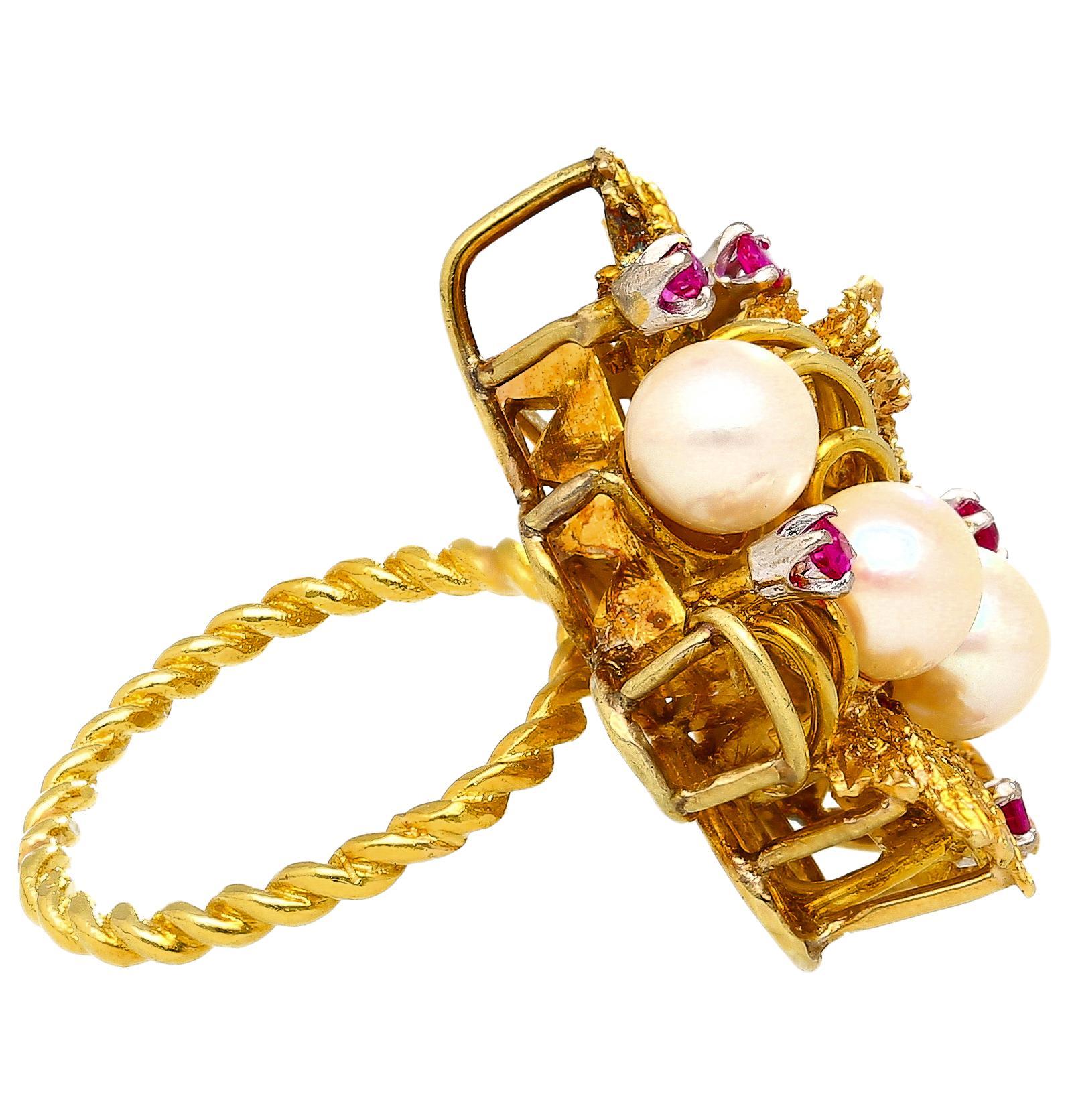 This vintage floral cocktail ring showcases three creamy 5mm cultured pearls and five rubies in a textured 18K yellow gold leaf motif. A striking twisted shank adds unique character and vintage charm to the overall design.

Details:
Item Type: