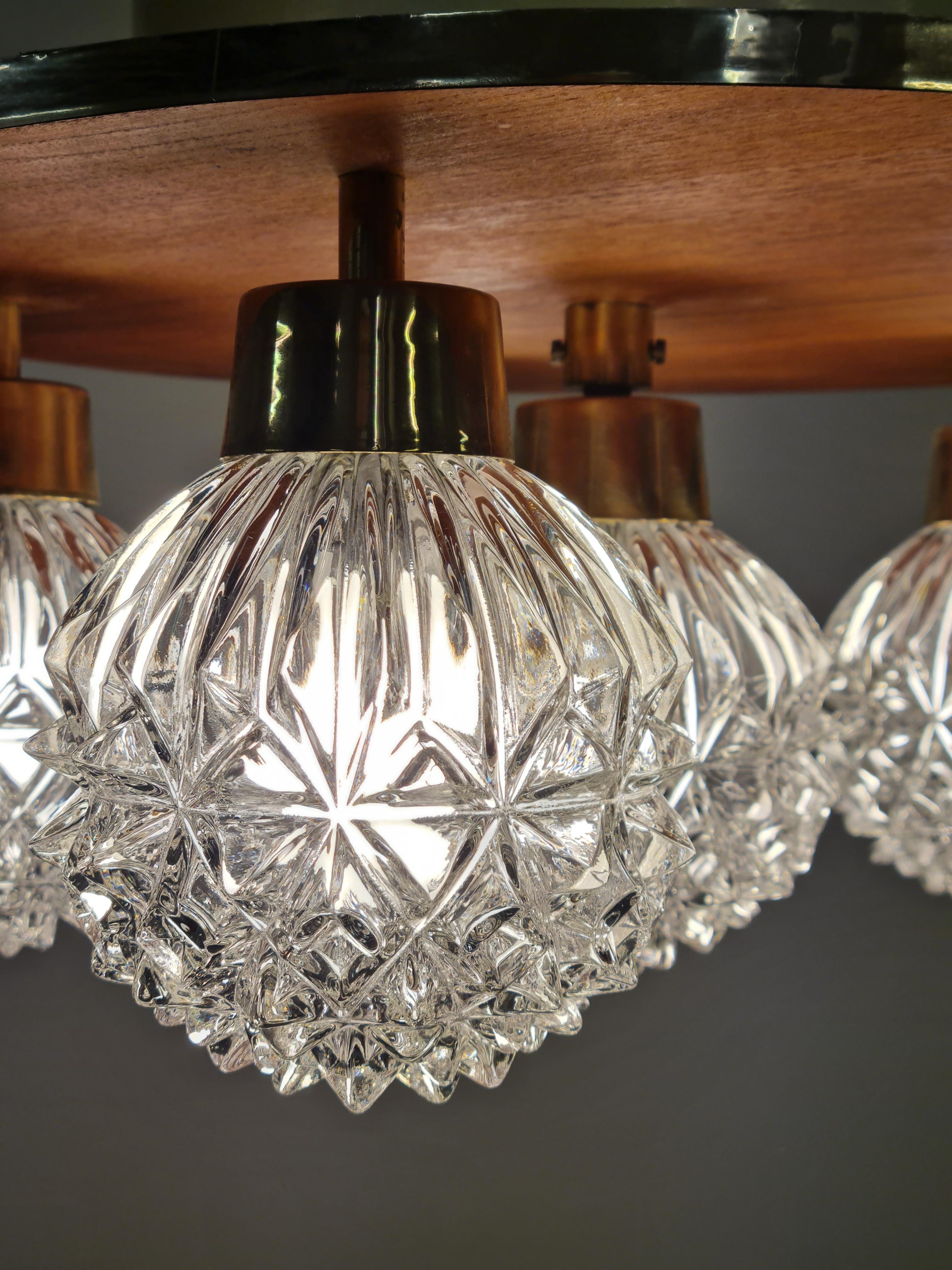 Une lampe encastrée moderne du milieu du siècle par les fabricants de lampes finlandais Hyval, numéro de modèle KP68. La lampe circulaire comporte 6 ampoules en verre transparent maintenues par des bras en laiton suspendus à un socle en teck. Cette