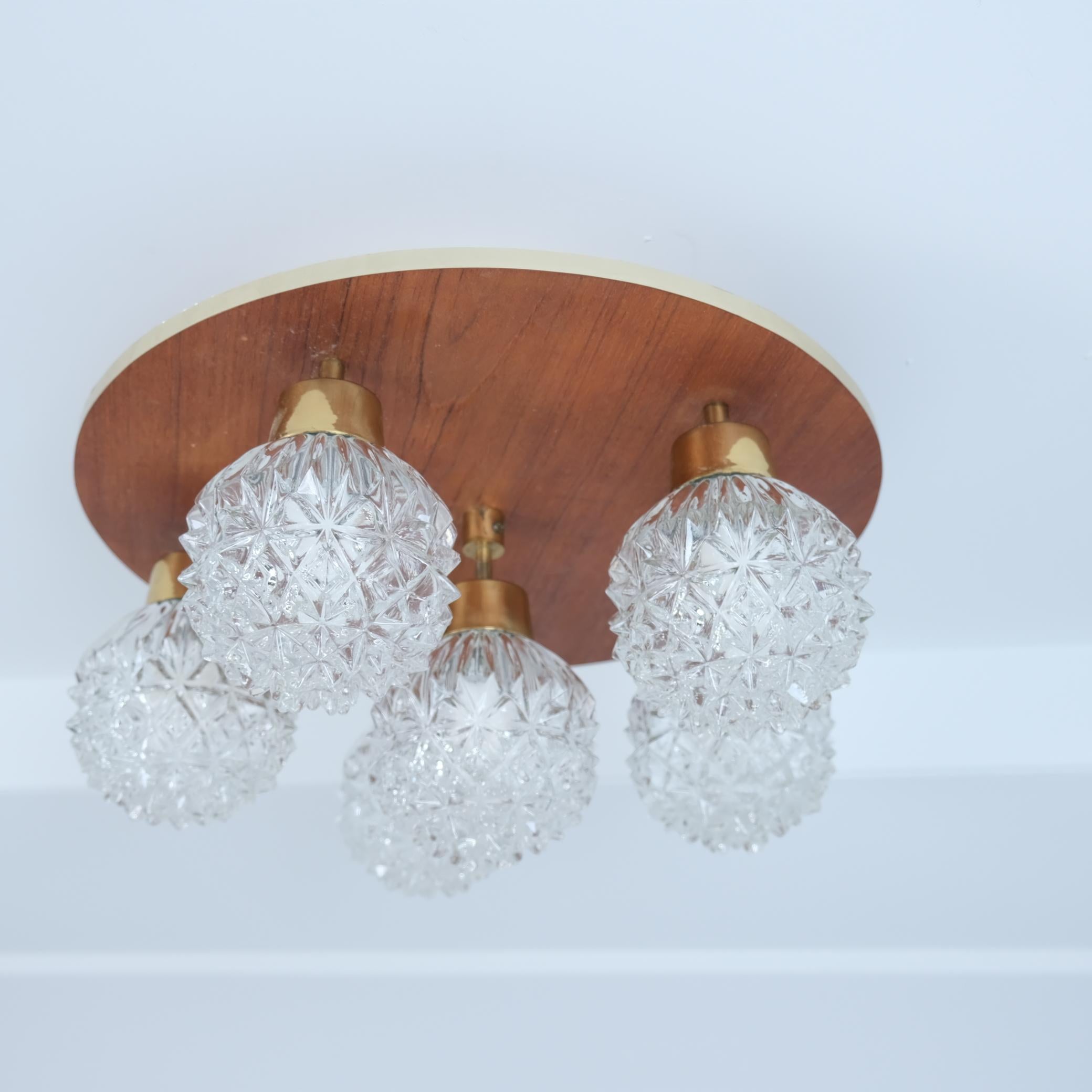 Une lampe encastrée moderne du milieu du siècle par les fabricants de lampes finlandais Hyval, numéro de modèle KP68. La lampe circulaire comporte 6 ampoules en verre transparent maintenues par des bras en laiton suspendus à un socle en teck. Cette