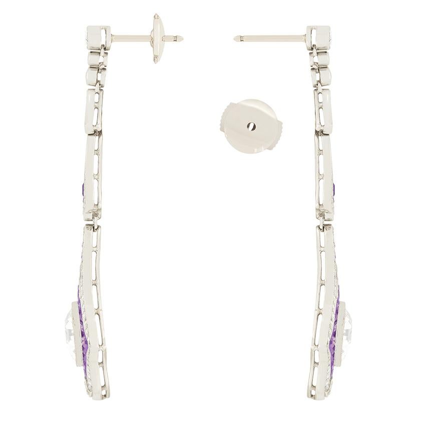 A phenomenal pair of vintage drop earrings composed of diamonds and amethysts. A fabulous pair of old cut diamonds weighing 3.00 carat each are rub over set on the bottom section of each earring. They have been graded as I-J in colour and VS1 in