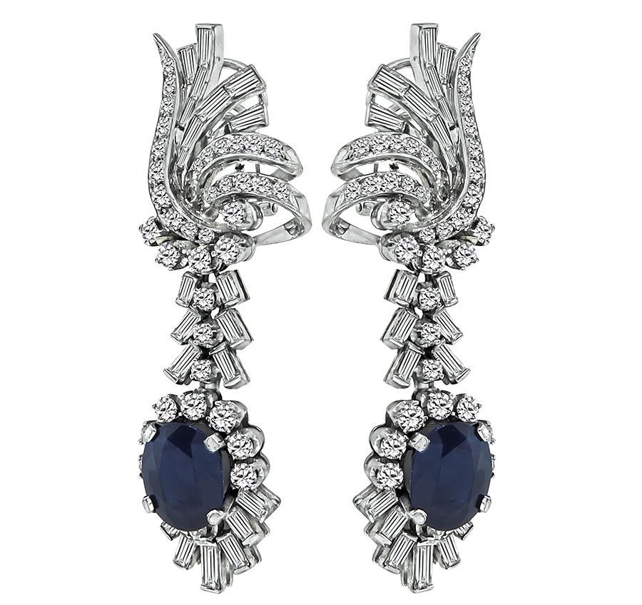 This is a charming pair of 14k white gold dangling earrings. The earrings feature lovely cushion cut sapphires that weigh approximately 6.00ct. The sapphires are accentuated by sparkling baguette and round cut diamonds that weigh approximately