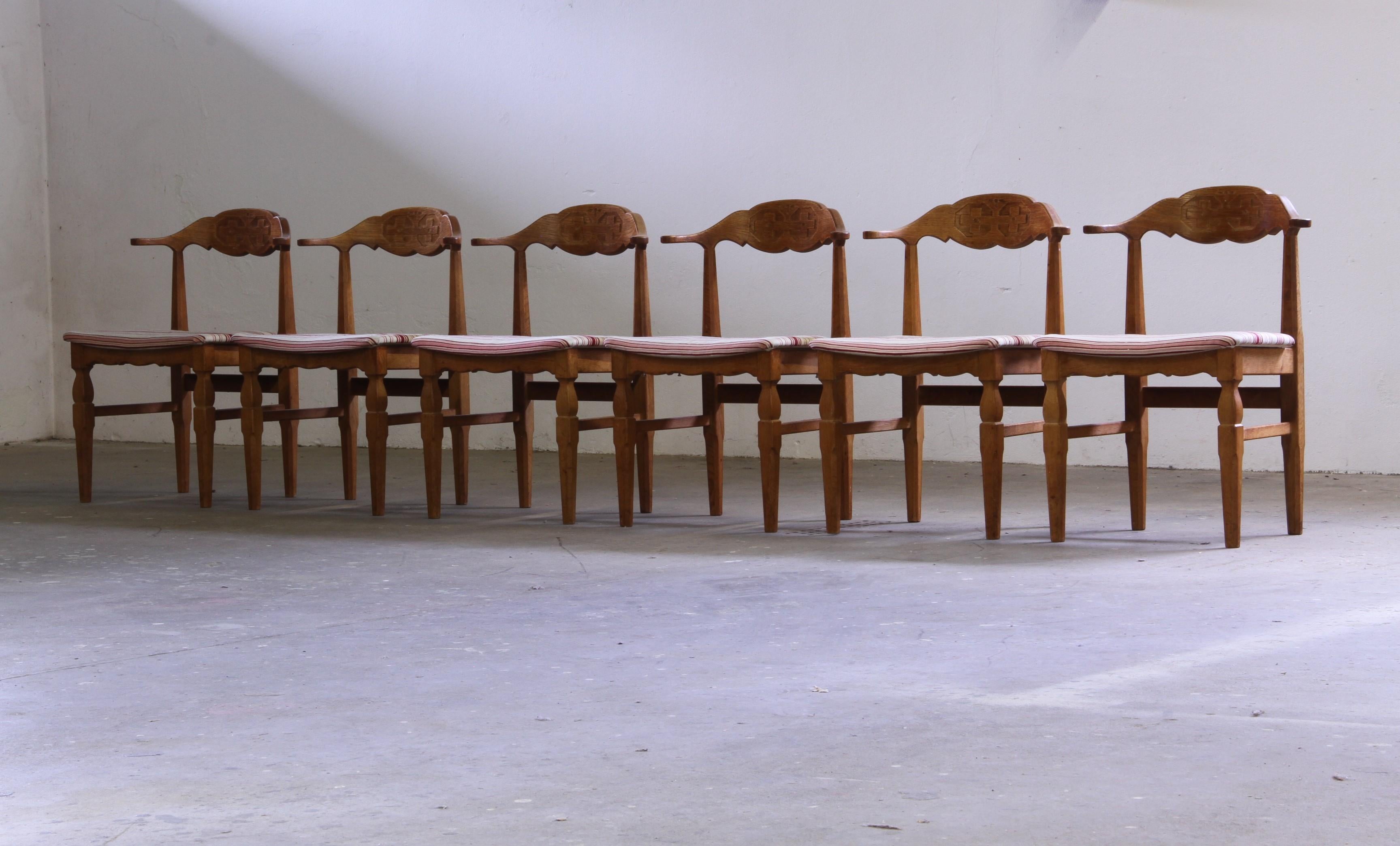 Cette magnifique chaise en chêne danois incarne le charme du design moderne du milieu du siècle dernier combiné à des influences baroques brutales dans l'esprit de Henning Kjærnulf. Le dossier sculpté présente des motifs symétriques frappants, une