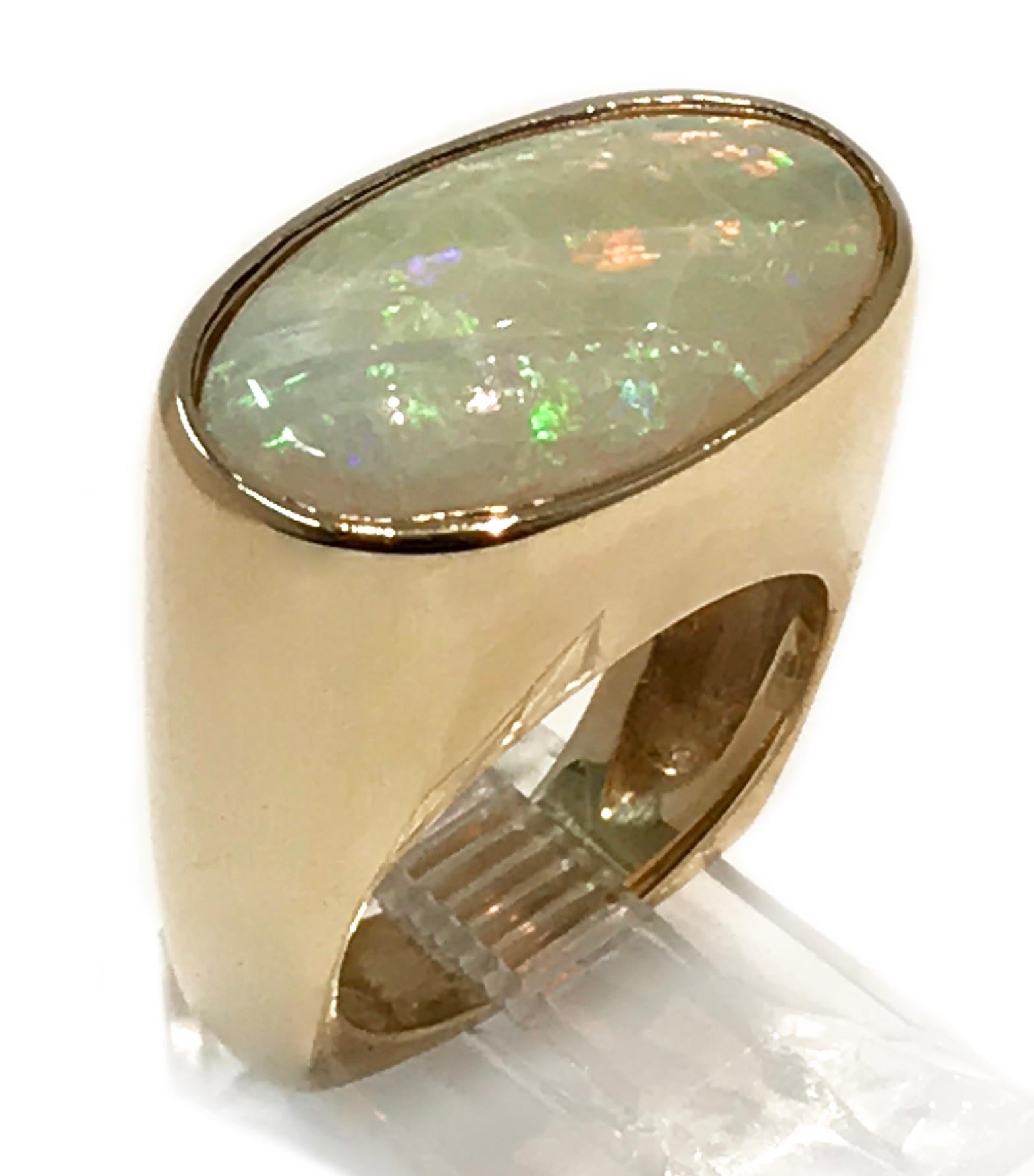 Vintage Opal 14k Yellow Gold Wide Band Ring. There are glorious bursts of colors in this large bezel-set oval Opal, a true statement piece. The ring is size 7. The ring has a total weight of 16.89 grams.