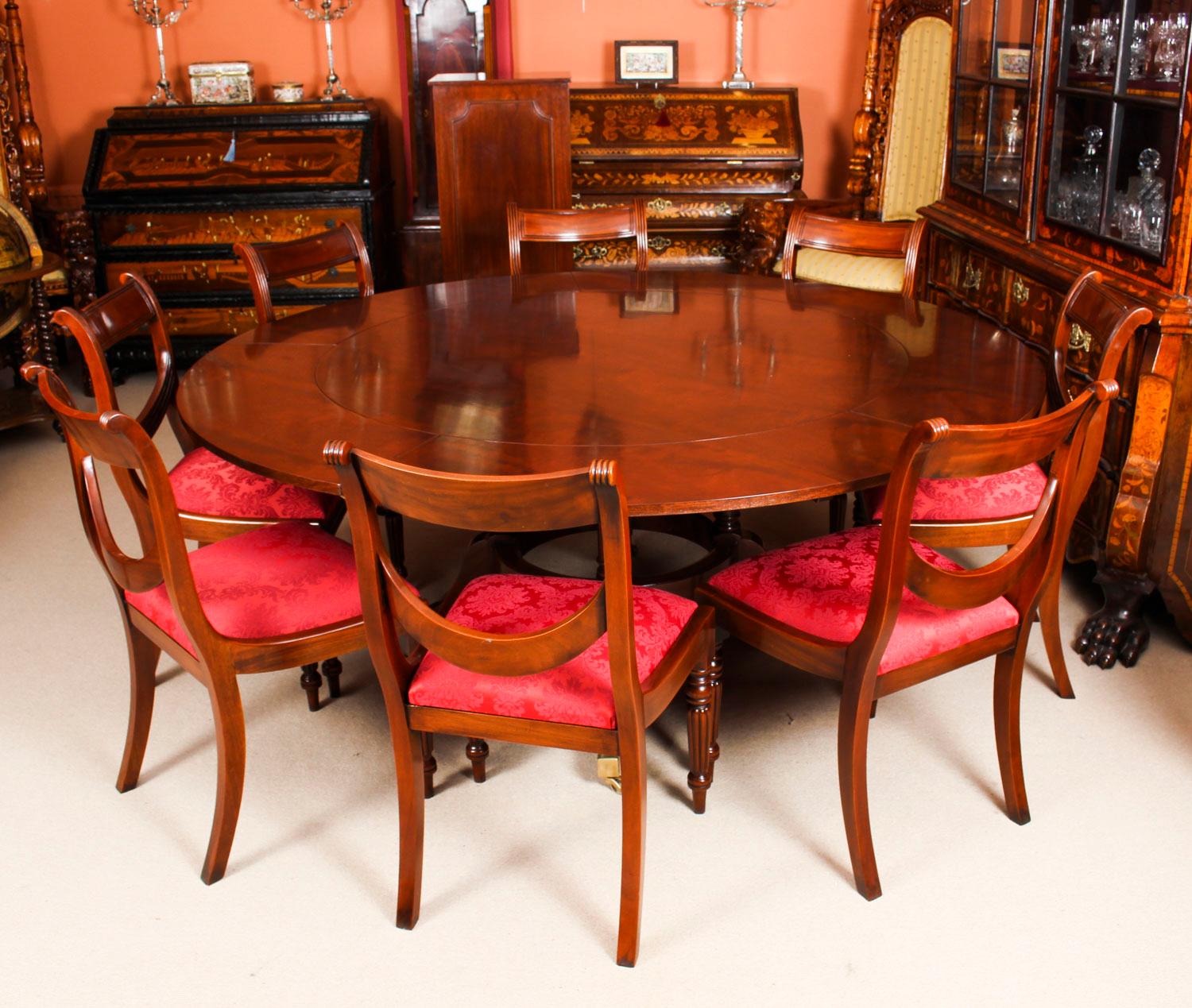 This is a beautiful Regency Revival Jupe style flame mahogany circular extending dining table, dating from the mid 20th Century.

The table has a solid mahogany top with five peripheral leaves that can be added around the circumference. It is raised