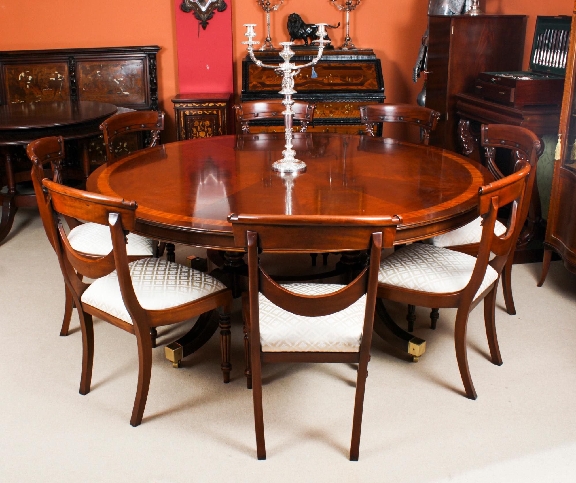 A beautiful Vintage Regency Revival dining table complete with the matching set of eight Regency style swagback dining chairs.

The flame mahogany veneers on the top have been arranged so as to give a sunburst effect and it is finished off by the