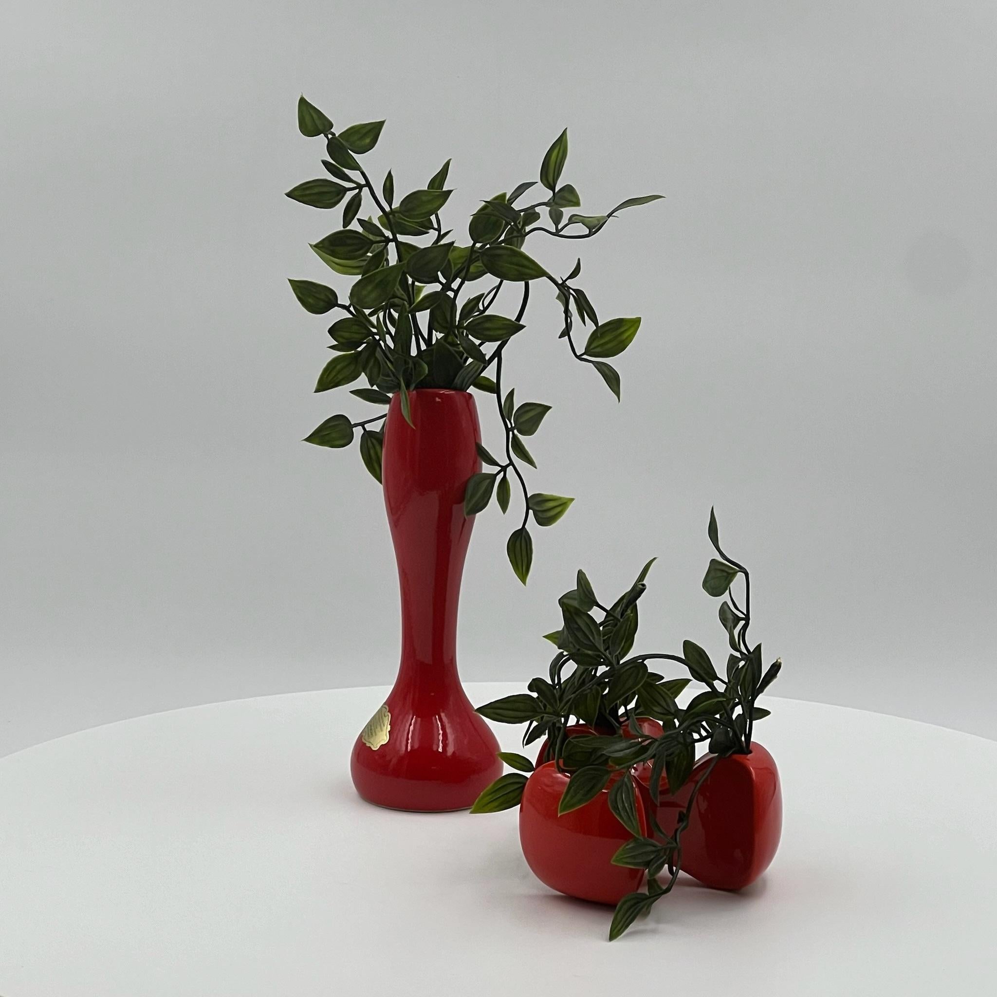 Spruce up your decor with this stunning vintage 70s ceramic vase duo crafted in Italy. The taller vase, a Monica art ceramic, boasts a vibrant handcrafted design glazed in bold red, standing at 20 cm tall with a diameter of 7 cm.

Complementing its