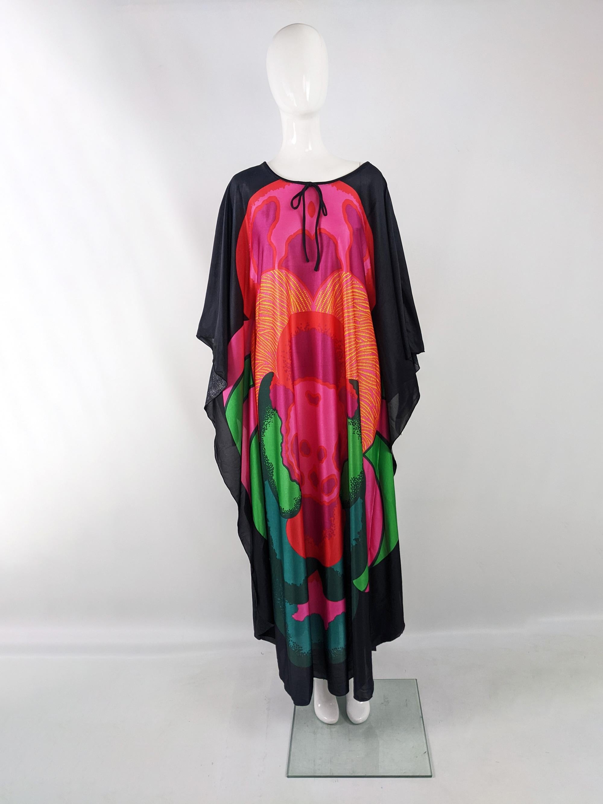 An incredible vintage womens maxi dress from the early 70s by quality British boutique designer, Clive Byrne of London. In a black synthetic fabric with an incredibly bold floral print in the centre of the front AND back. It has a sweet bow at the