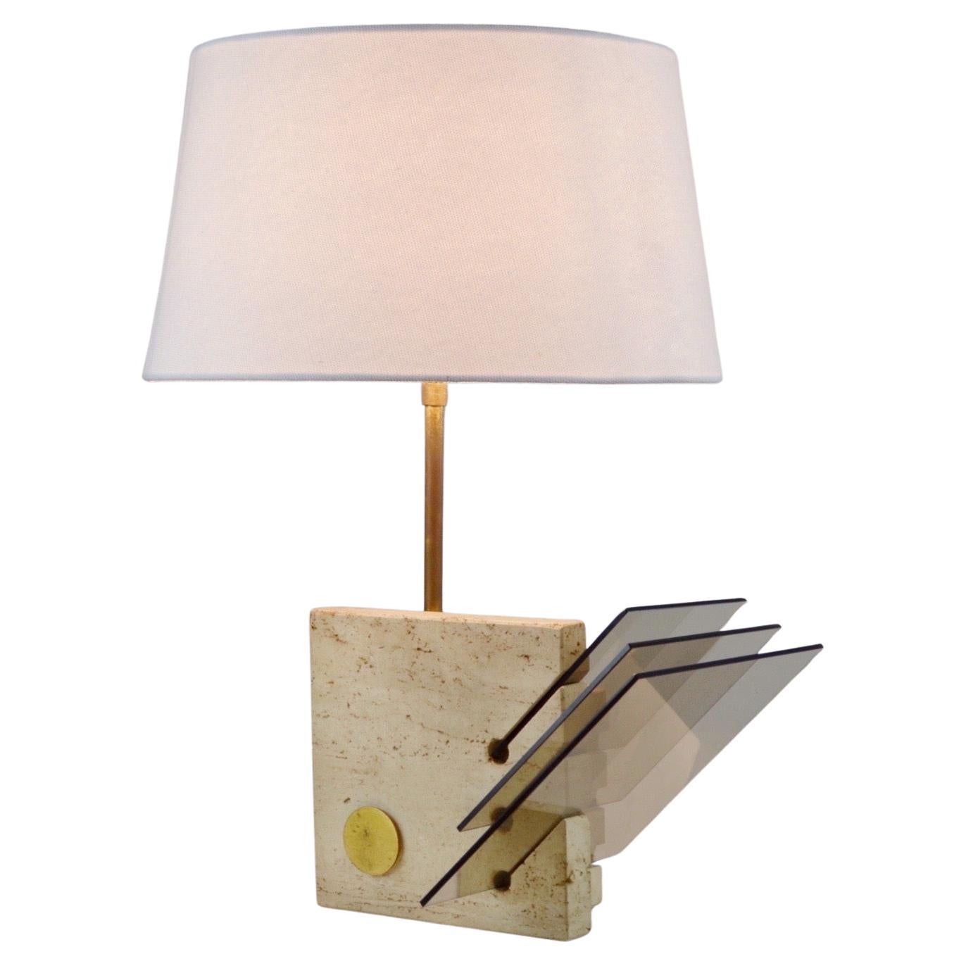 A stunning Italian lamp from the 1970s, attributed to Enzo Mari for Fratelli Manelli, seamlessly blending elegance and noble materials. Its base, composed of two solid travertine blocks connected by a patinated brass axis, forms a perfectly balanced