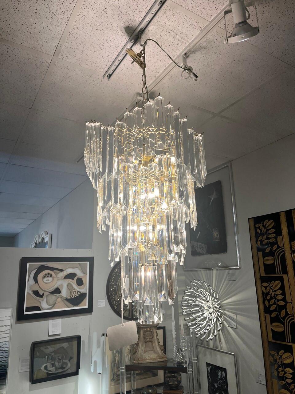 Elevate your space with a touch of retro glamour with this stunning Vintage 70's Lucite and Brass Cascading Waterfall Chandelier. Crafted with meticulous detail, this piece combines the sleek elegance of Lucite with the timeless allure of brass. The