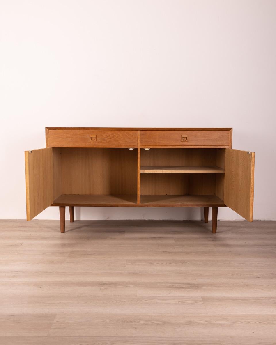 Sideboard in oak wood, has two drawers at the top and two hinged doors, Danish design, 1970s.

Conditions: In good condition, it shows signs of wear given by time.
Dimensions: Height 80 cm; Width 135 cm; Length 50 cm
Materials: Wood
Year Of