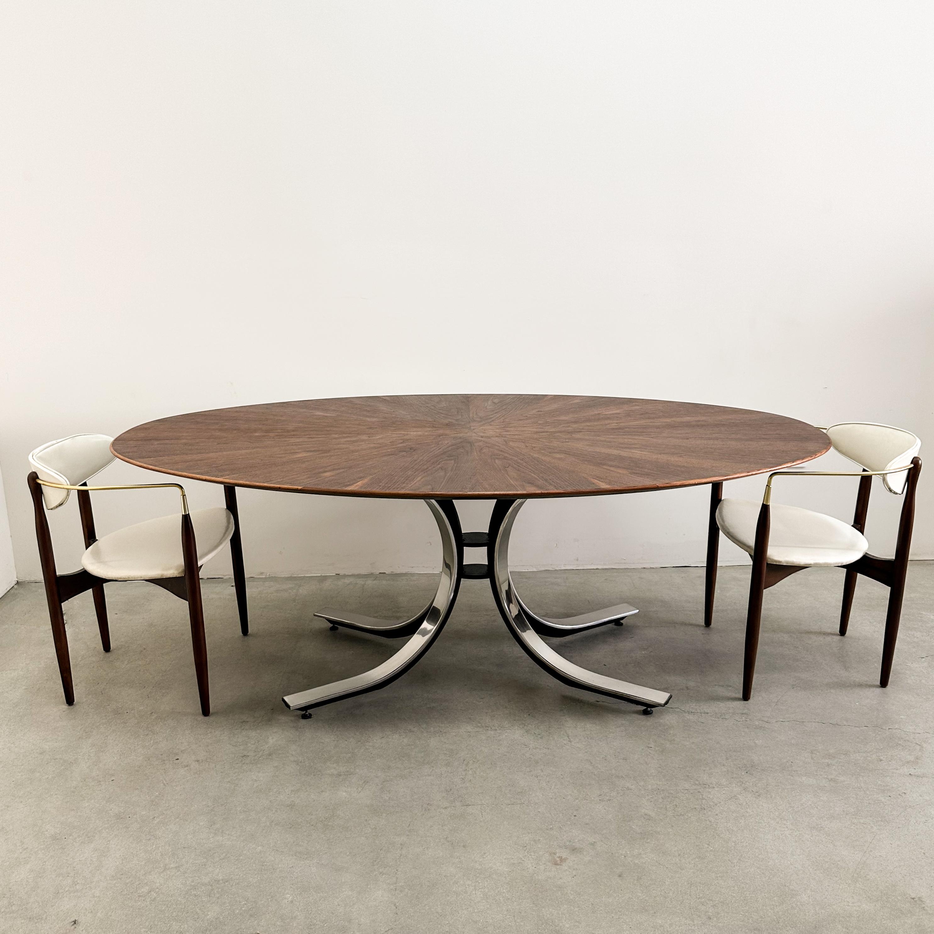 Often attributed to Osvaldo Borsani, this authentic 1970s Stow & Davis oval dining table has been confirmed as an original design. A striking example of mid-century modern furniture, it features a walnut starburst veneer top and a sculptural chrome
