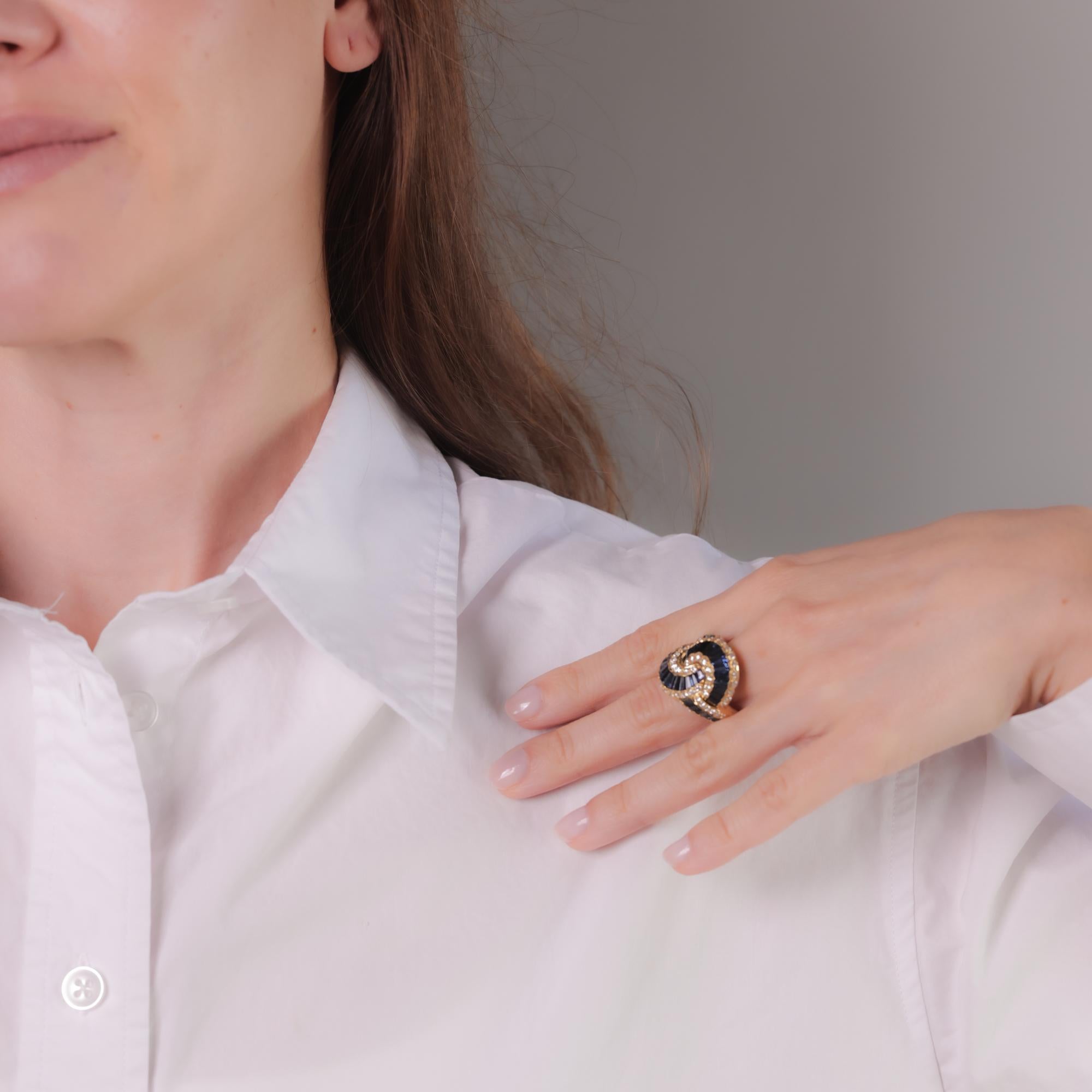 Este anillo vintage de oro amarillo de 18 quilates presenta aproximadamente 6 quilates de zafiros azules talla baguette cónicos y 68 diamantes brillantes redondos que suman aproximadamente 1,50 quilates, color E, claridad VS. Alrededor de la década