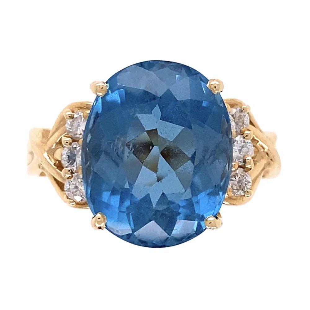 Simply Beautiful!  Blue Topaz and Diamond Gold Cocktail Ring. Centering a securely nestled Hand set Oval Blue Topaz, weighing approx. 7.50 Carat. Both sides of Ring Hand set with Diamonds, approx. 0.25tcw. Hand crafted 14K Yellow Gold mounting. Ring