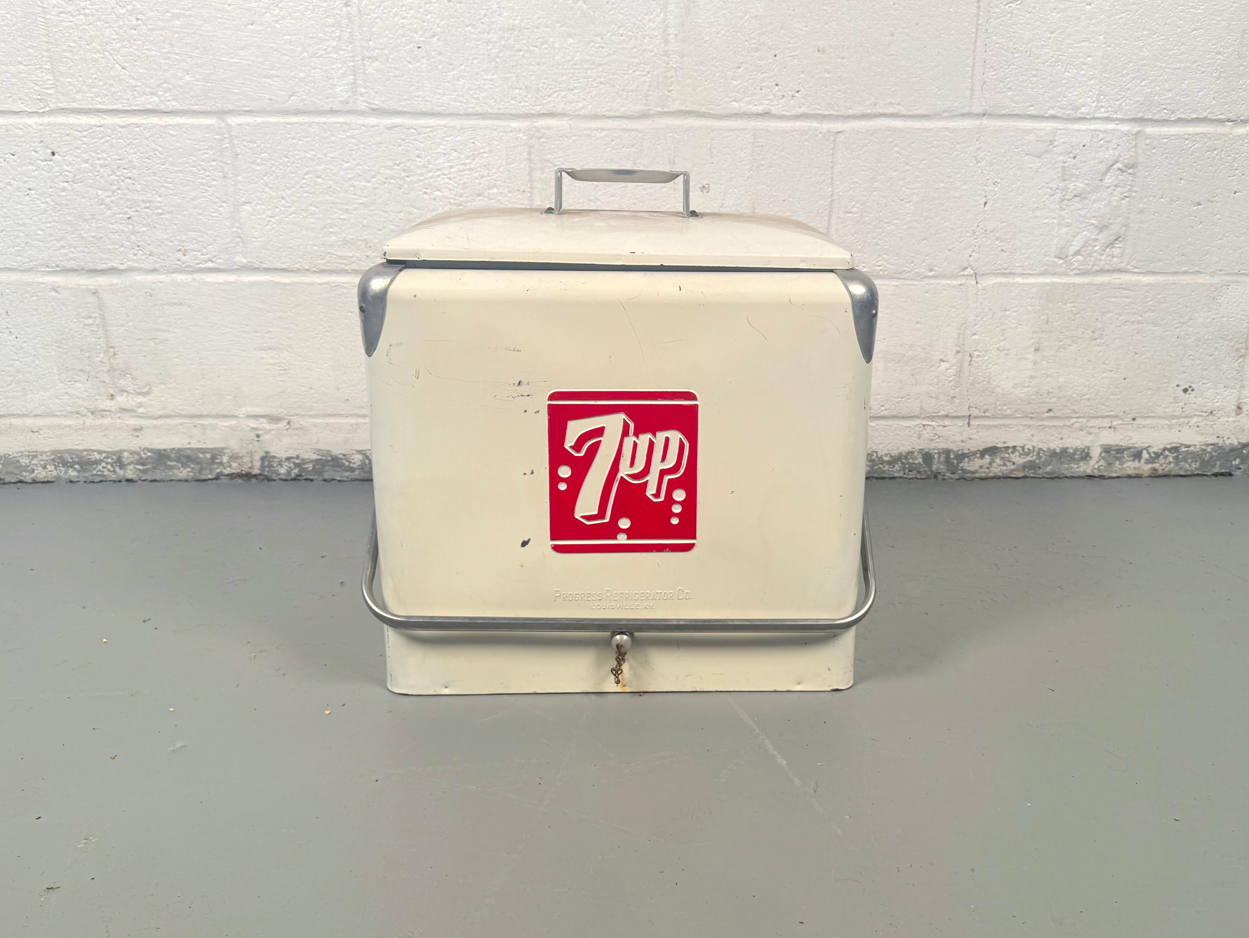 Servez une tranche d'Americana avec ce charmant refroidisseur de bouteilles 7UP en métal, fabriqué par la Progress Refrigerator Company de Louisville, Kentucky, entre 1950 et 1960. Cette glacière classique est un objet de conversation qui sert à la