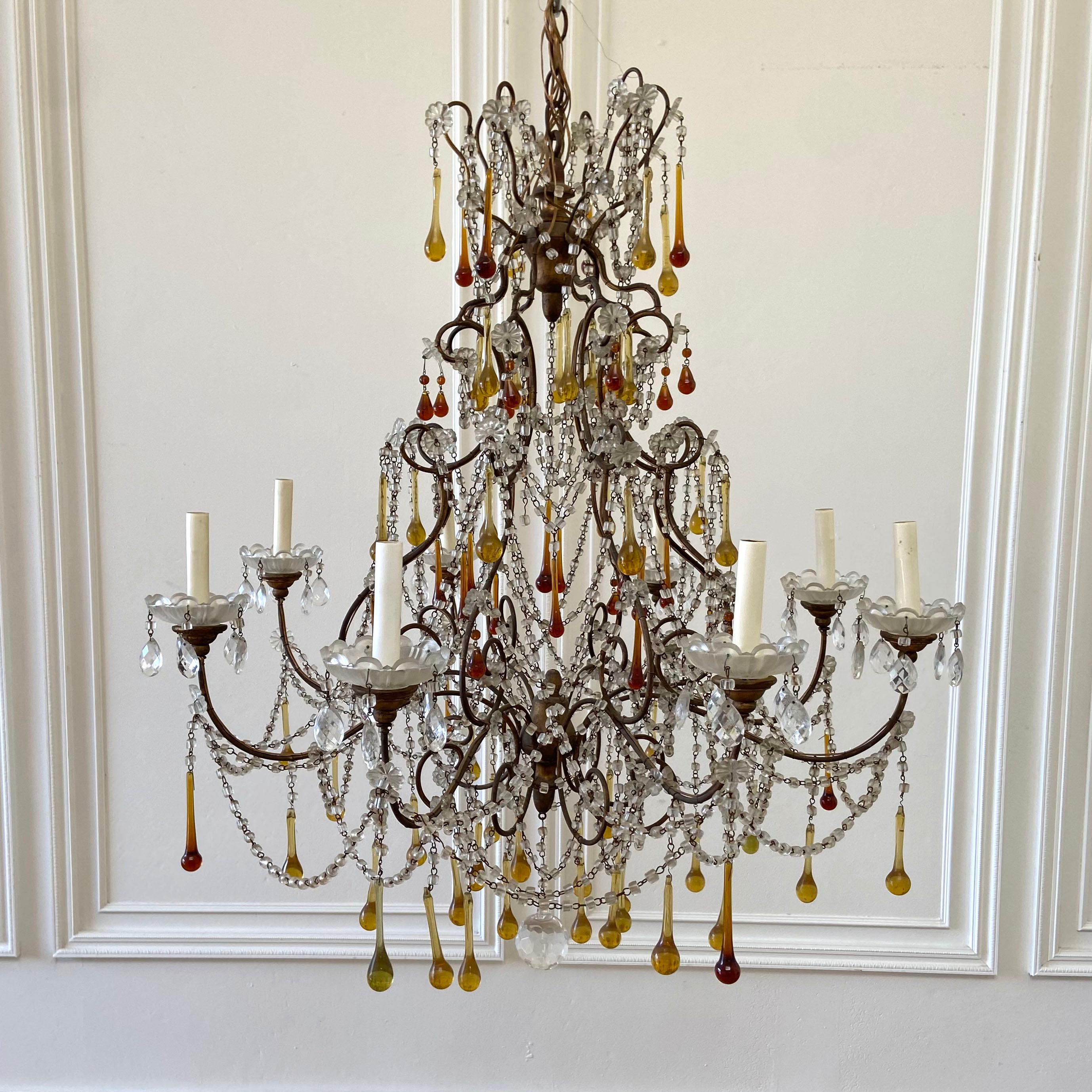 Vintage macaroni beaded chandelier with amber crystals
Dark iron frame chandelier has a deep bronze color, with clear, and clouded macaroni
style beads. Glass bobéches cups, with deep amber drop crystals. They could be removed if you did not want