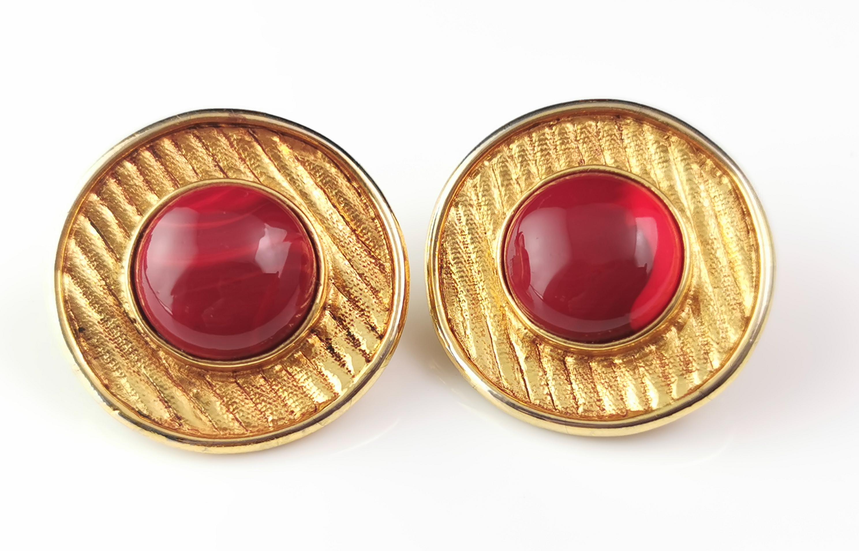 A gorgeous pair of vintage c1980s clip on earrings by Antigona Paris.

Lush rich gold tone circles with a textured line engraved finish featuring a large warm red faux agate cabochon to the centre.

They have a clip fitting to the reverse for