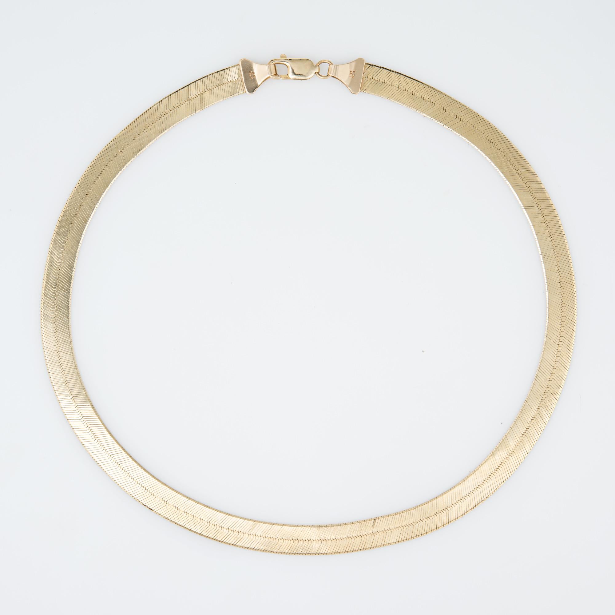 Elegant and finely detailed 14 karat yellow gold herringbone necklace (circa 1980s).  

The necklace measures 18 inches in length and sits nicely just below the nape of the neck. The necklace measures 9mm wide (0.35 inches). The necklace is great