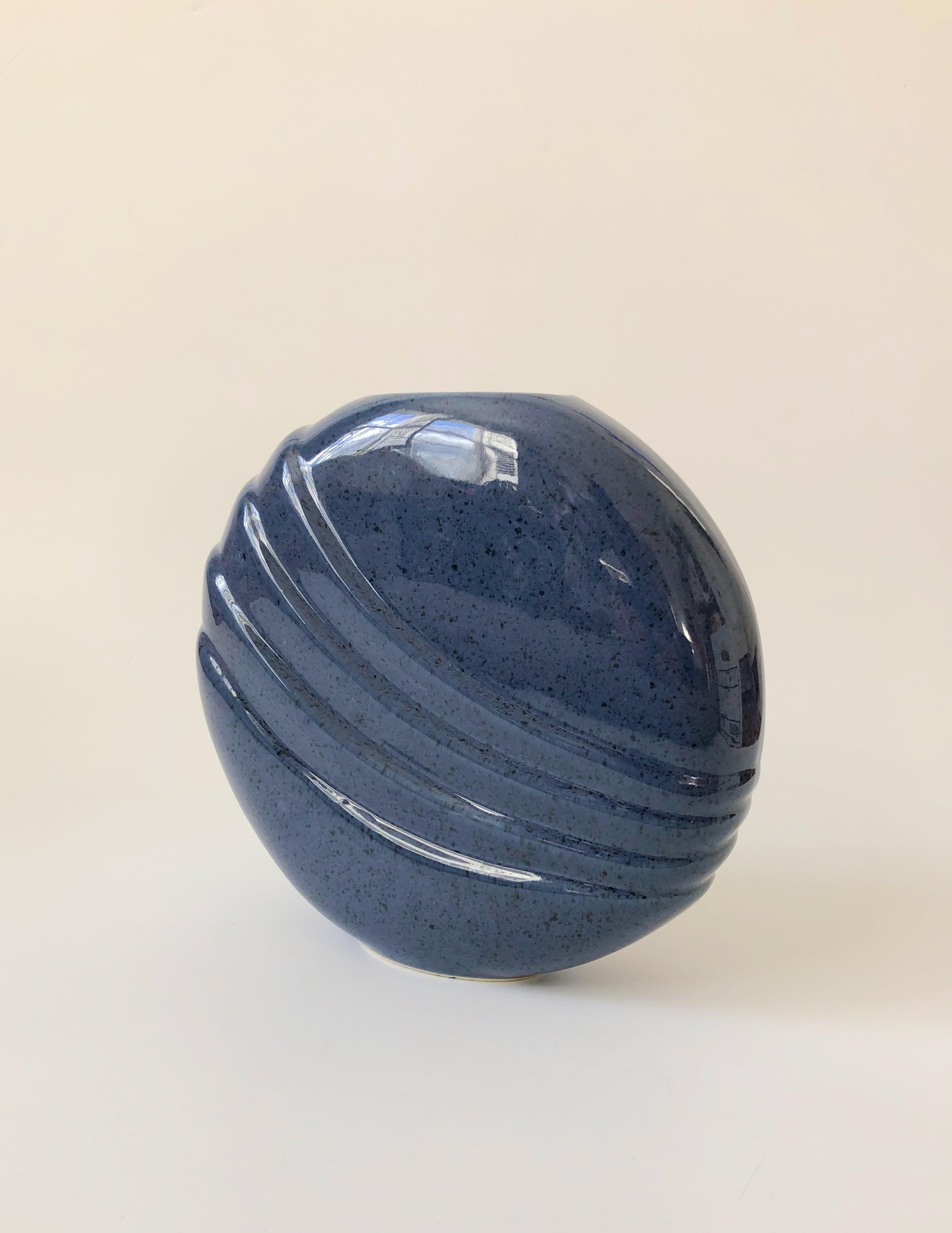 A wonderful vintage 80s modern ceramic vase. High gloss speckled blue glaze with a curved embossed design formed into the surface. A great sculptural piece with an unusual flat circular shape.
 