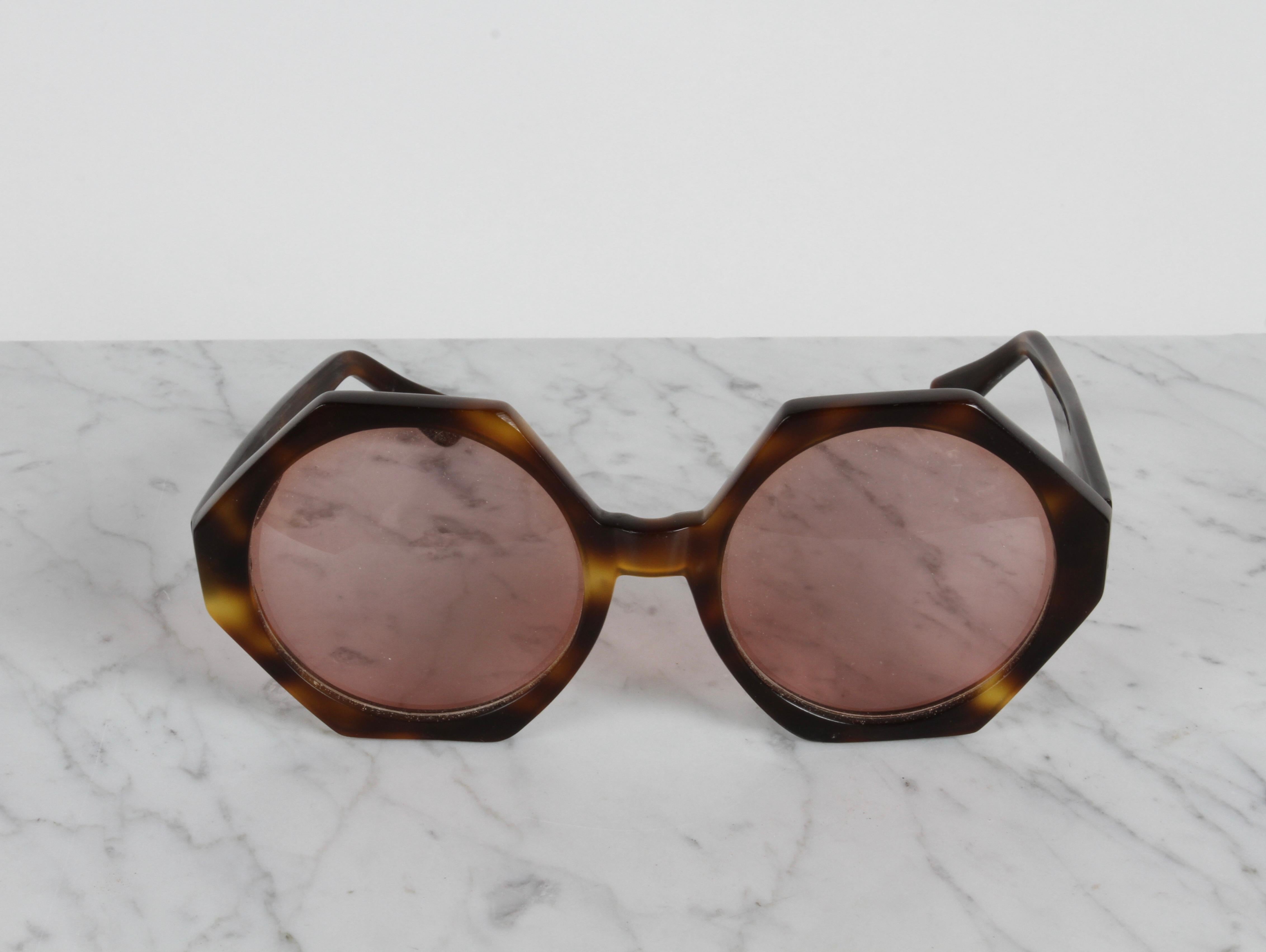 Si tratta di un bel paio di occhiali da sole vintage di Oliver Goldsmith con montatura HEX in tartaruga e lenti rosa. 

Marcato sui telai :  OG Oliver Goldsmith Fatto a mano in Inghilterra 
L'ingombro interno tra i bracci è di 5.75