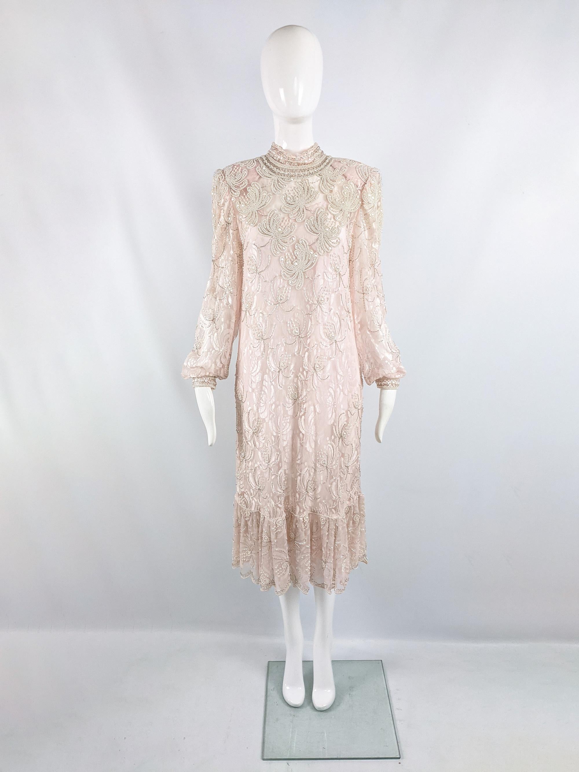A fabulous vintage womens dress from the 80s in a pink sheer lace, heavily embellished with beads and faux pearls. It comes with a lightweight, sleeveless slip dress. It has structured shoulder pads, a loose fit and a mock neck. 

Size: Unlabelled;