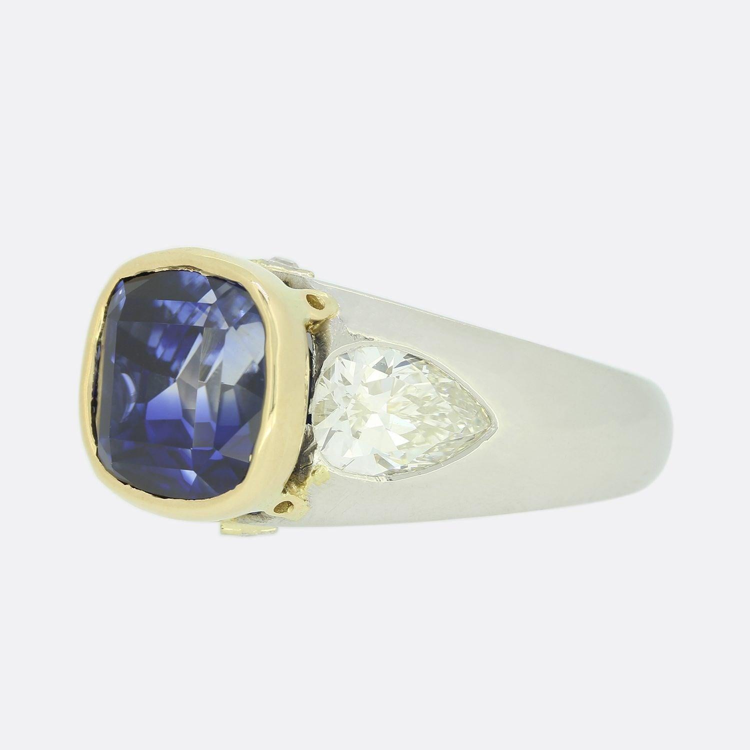 This is a wonderful vintage sapphire and diamond ring. The cushion-cut sapphire is untreated, of Ceylon origin and a mid to dark blue tone. Each shoulder is set with a bright white large pear cut diamond which highly compliments the blue of the